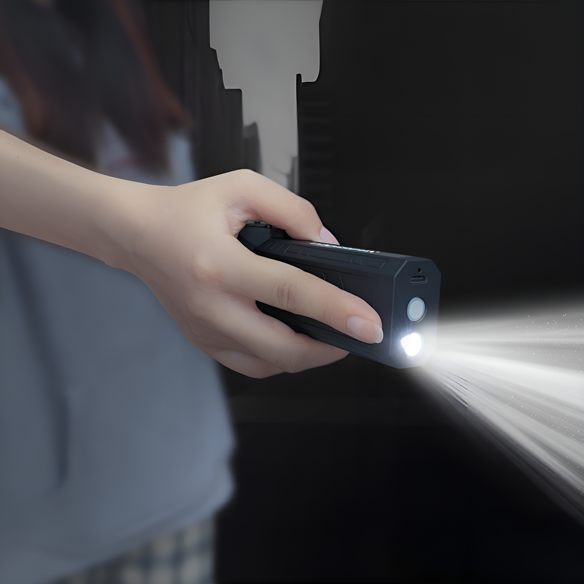 Eine Hand hält eine schwarze Taschenlampe, die einen hellen Lichtstrahl aussendet.