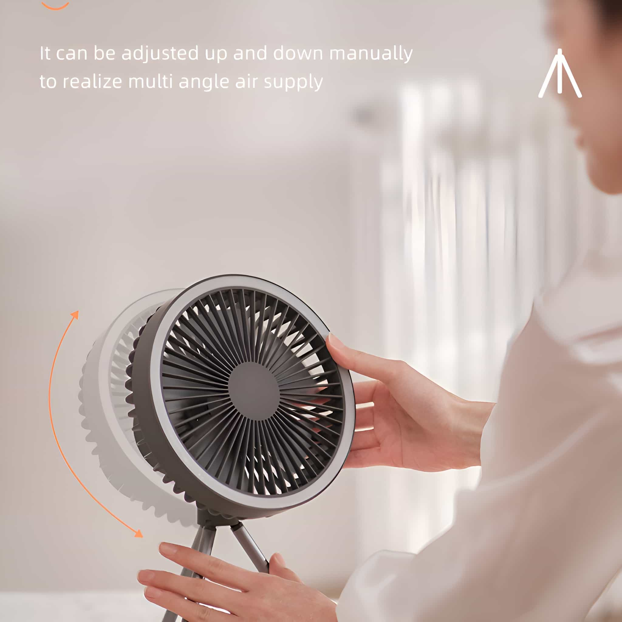 Ein kleiner Ventilator mit rotierenden Blättern. Eine Person stellt den Winkel manuell ein.