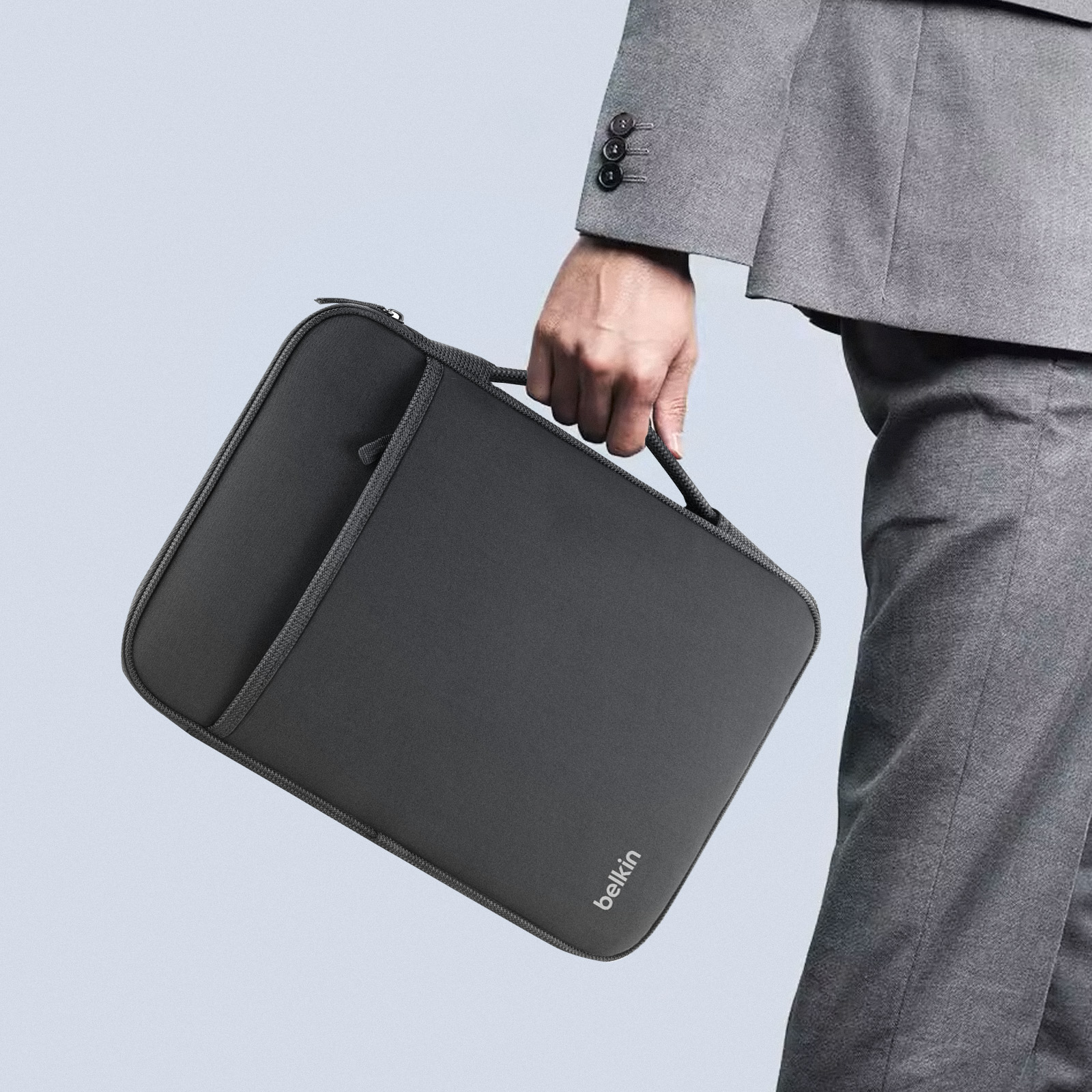 Una persona che tiene una custodia per laptop grigio scuro con il logo Belkin.