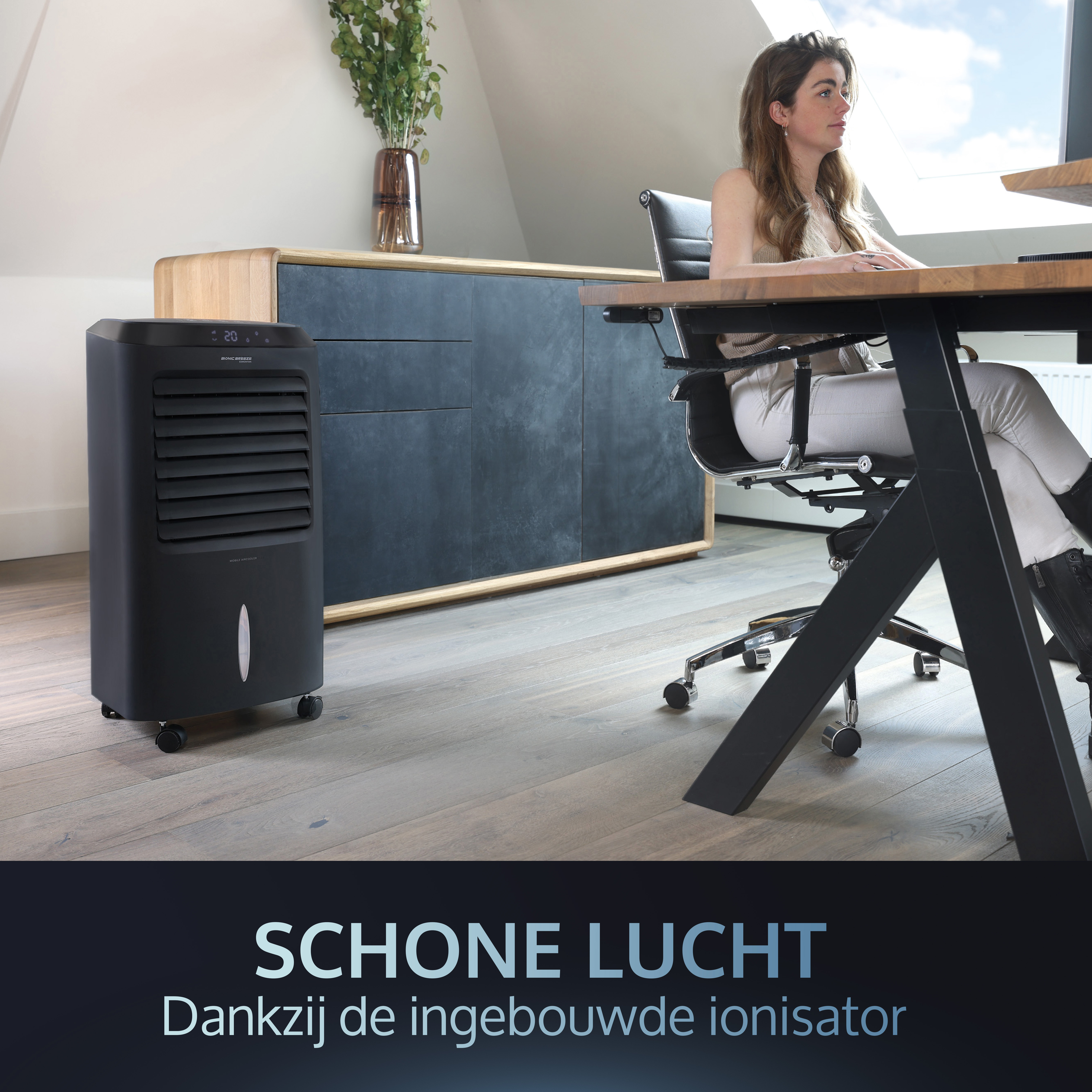 Schwarzer Luftkühler in einem Raum, Frau arbeitet am Schreibtisch.
