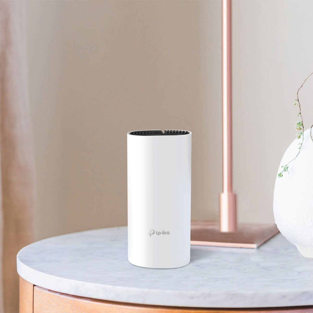 Ein weißer zylindrischer TP-Link WLAN-Router auf einem Marmortisch. Im Hintergrund eine Lampe und eine Vase.