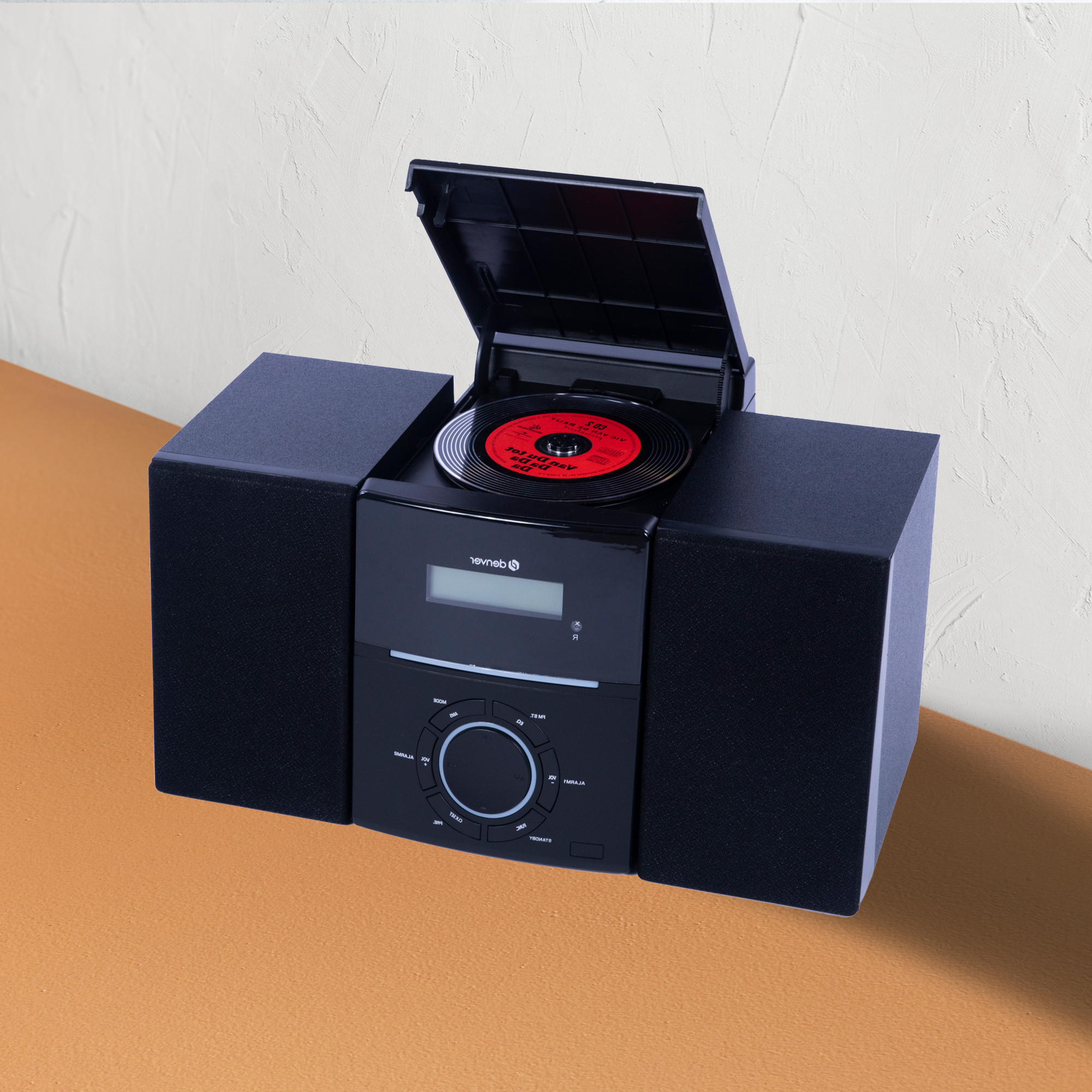 Czarny system stereo z głośnikami i gramofonem na górze, odtwarzający czerwoną płytę winylową.