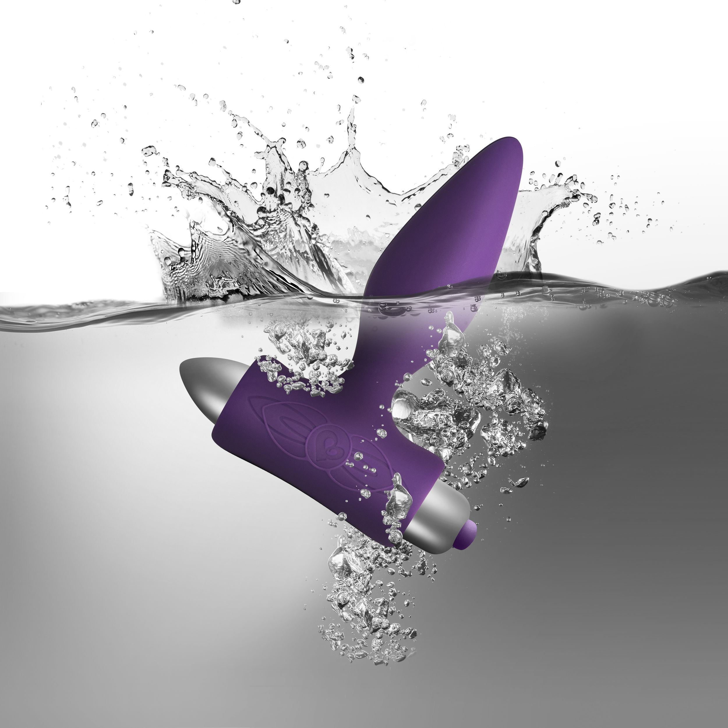 Ein lila Sexspielzeug im Wasser, mit Wasserspritzer, weißer und grauer Hintergrund.