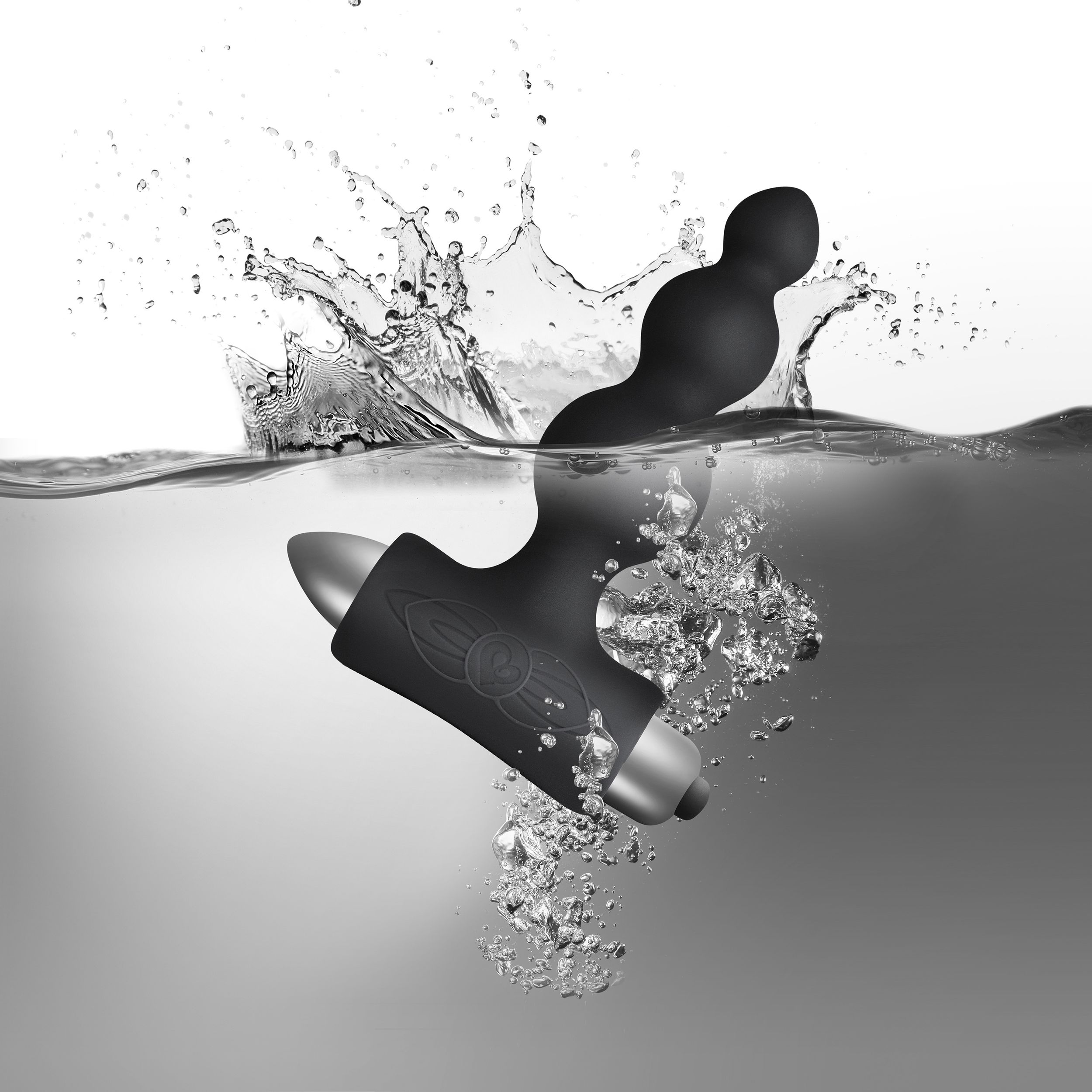 Schwarzes Sexspielzeug unter Wasser, mit Wasserspritzern und Blasen.