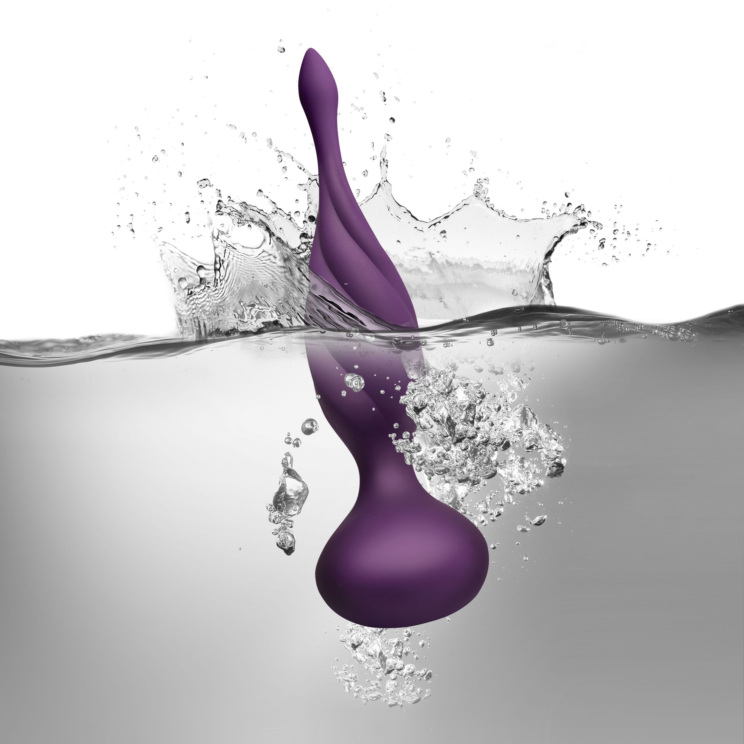 Lila Sexspielzeug, das ins Wasser spritzt und auf weißem Hintergrund einen Spritzer und Blasen erzeugt.