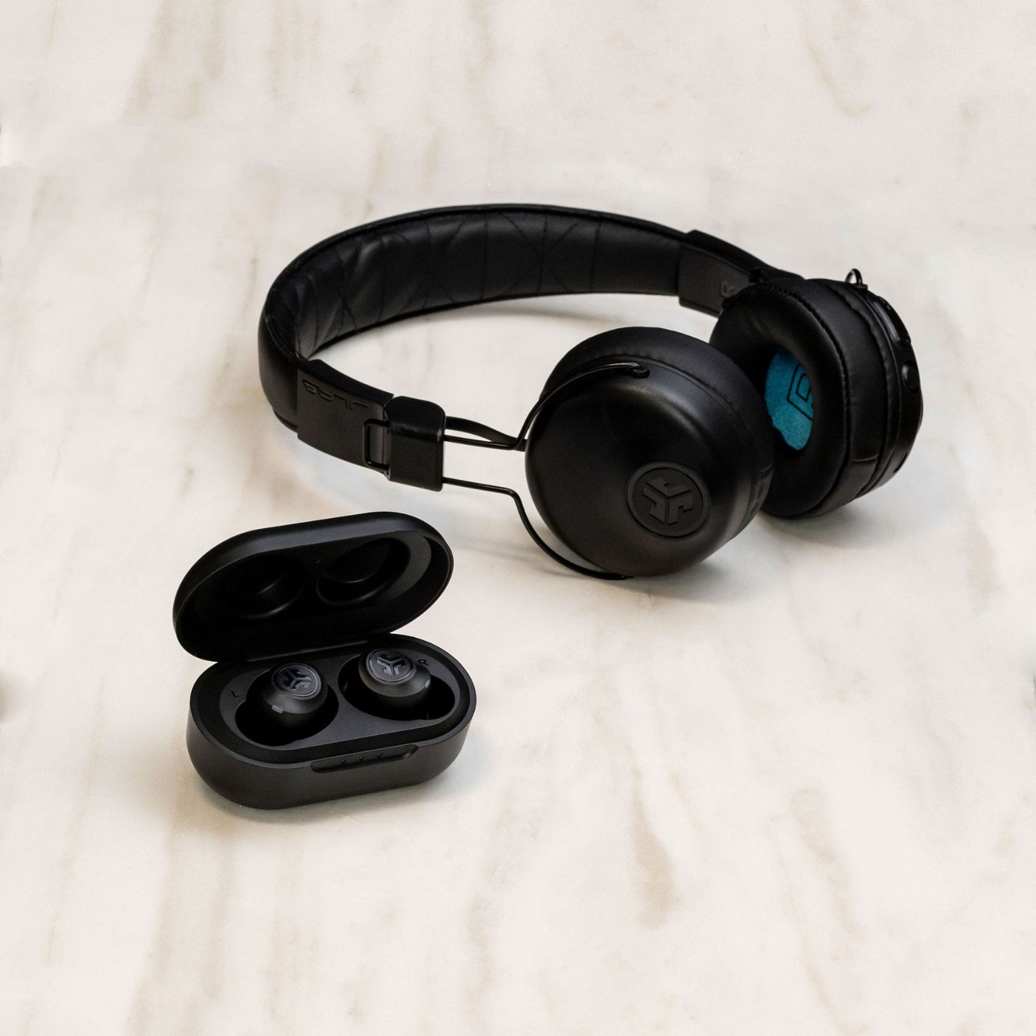 Auriculares y auriculares inalámbricos negros en un estuche de carga, sobre una superficie marmolada.