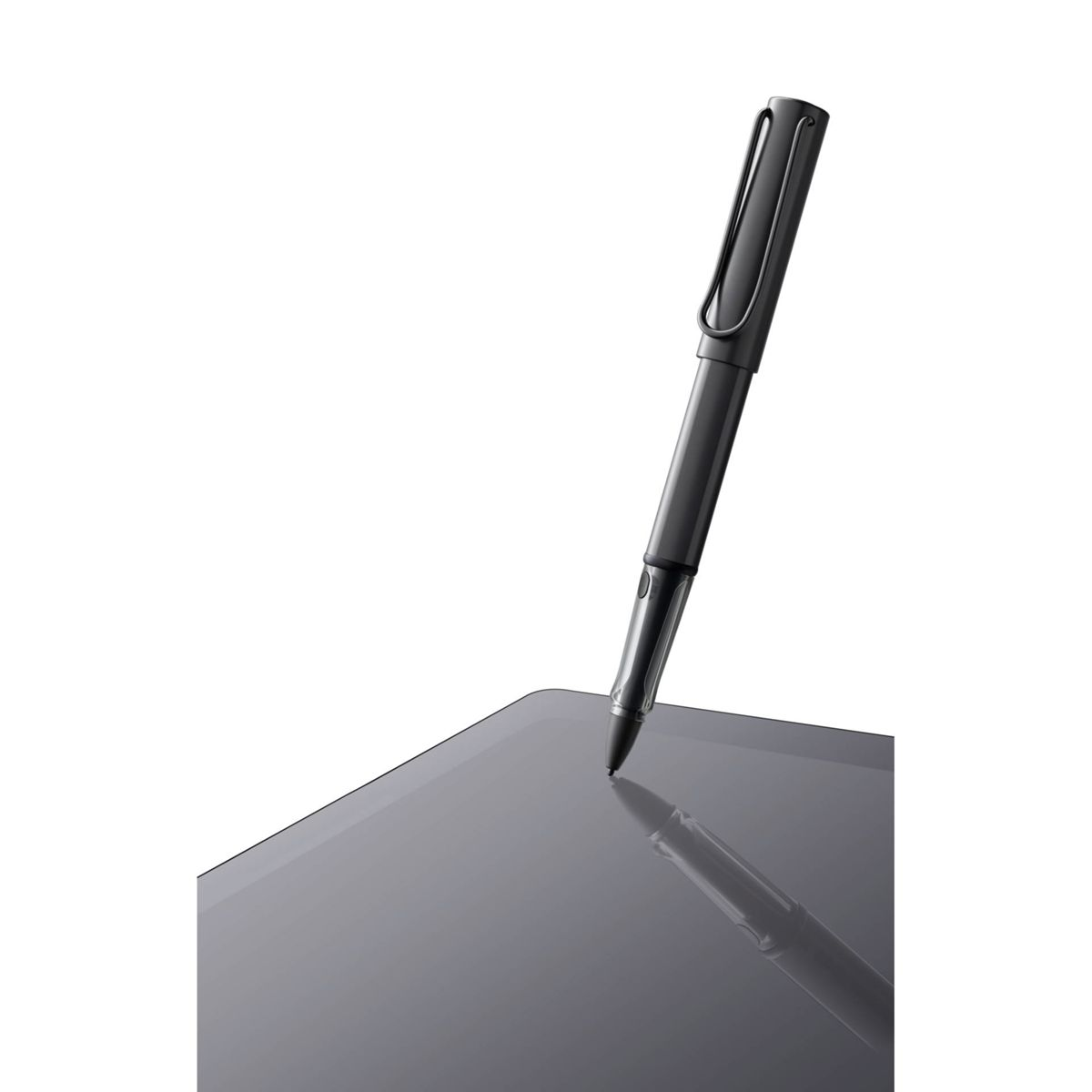 Ein schwarzer Lamy-Stift auf einem grauen Tablet mit Spiegelung. Der Stift ist abgewinkelt.