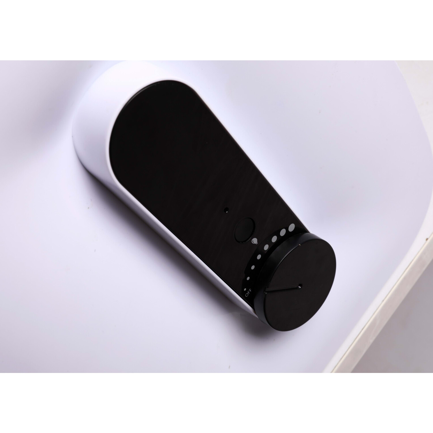 Biało-czarne urządzenie z pokrętłem na białej powierzchni.