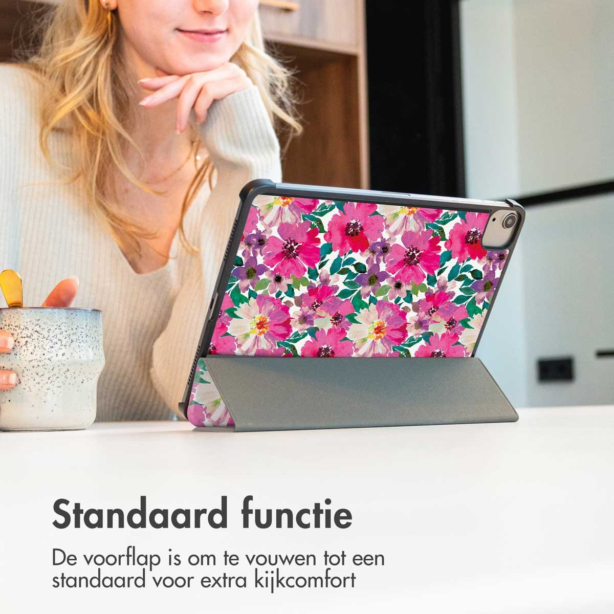 A woman is looking at a tablet with a floral case on a table. The case is open, acting as a stand.