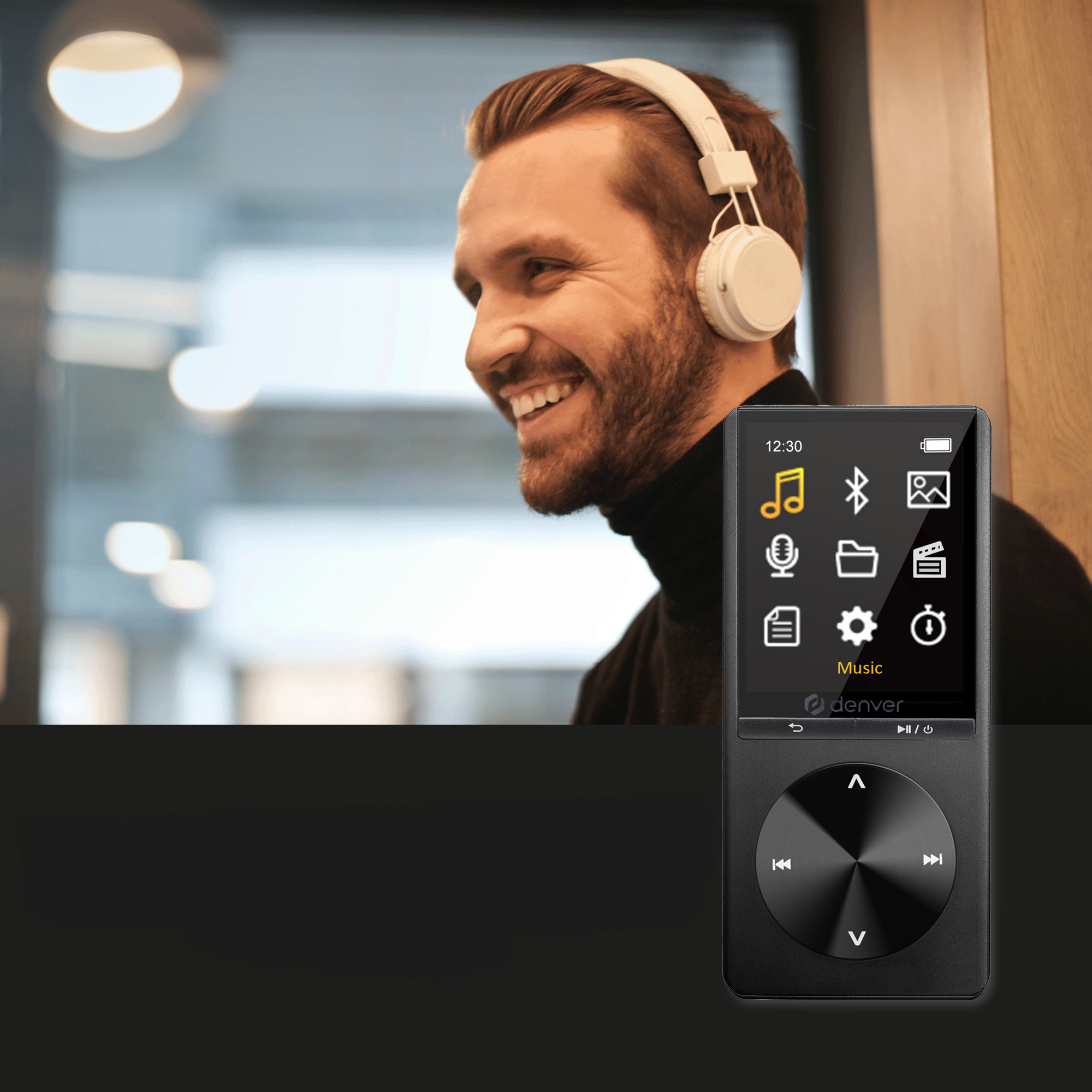 A man with headphones smiles, looking at a black MP3 player. The screen shows music and settings icons.