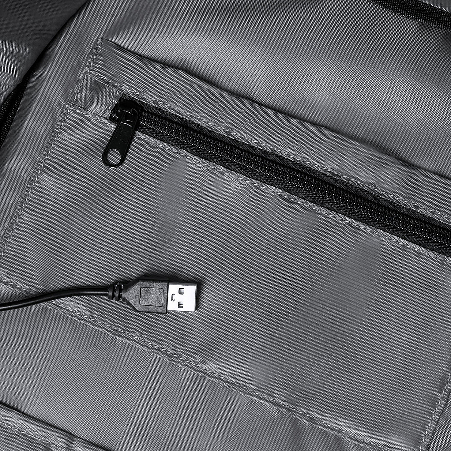 Primer plano de tela gris con cremallera y puerto USB, mostrando el conector.