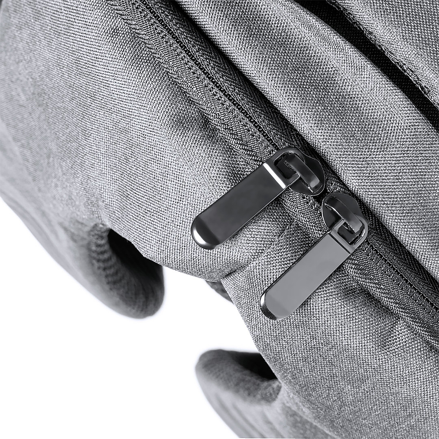 Primer plano de una mochila gris con dos cremalleras metálicas.