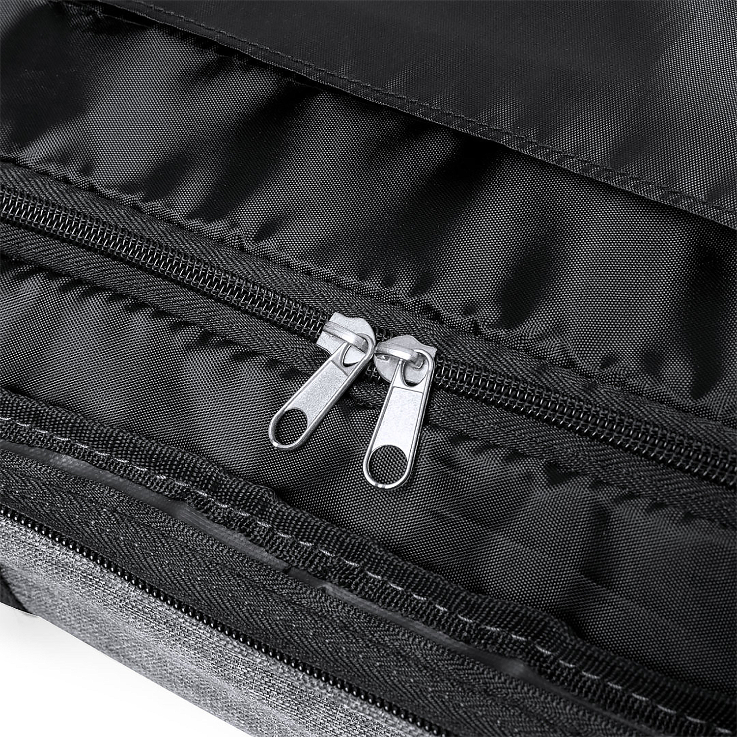 Nahaufnahme einer schwarzen Tasche mit zwei silbernen Reißverschlüssen. Innenansicht.