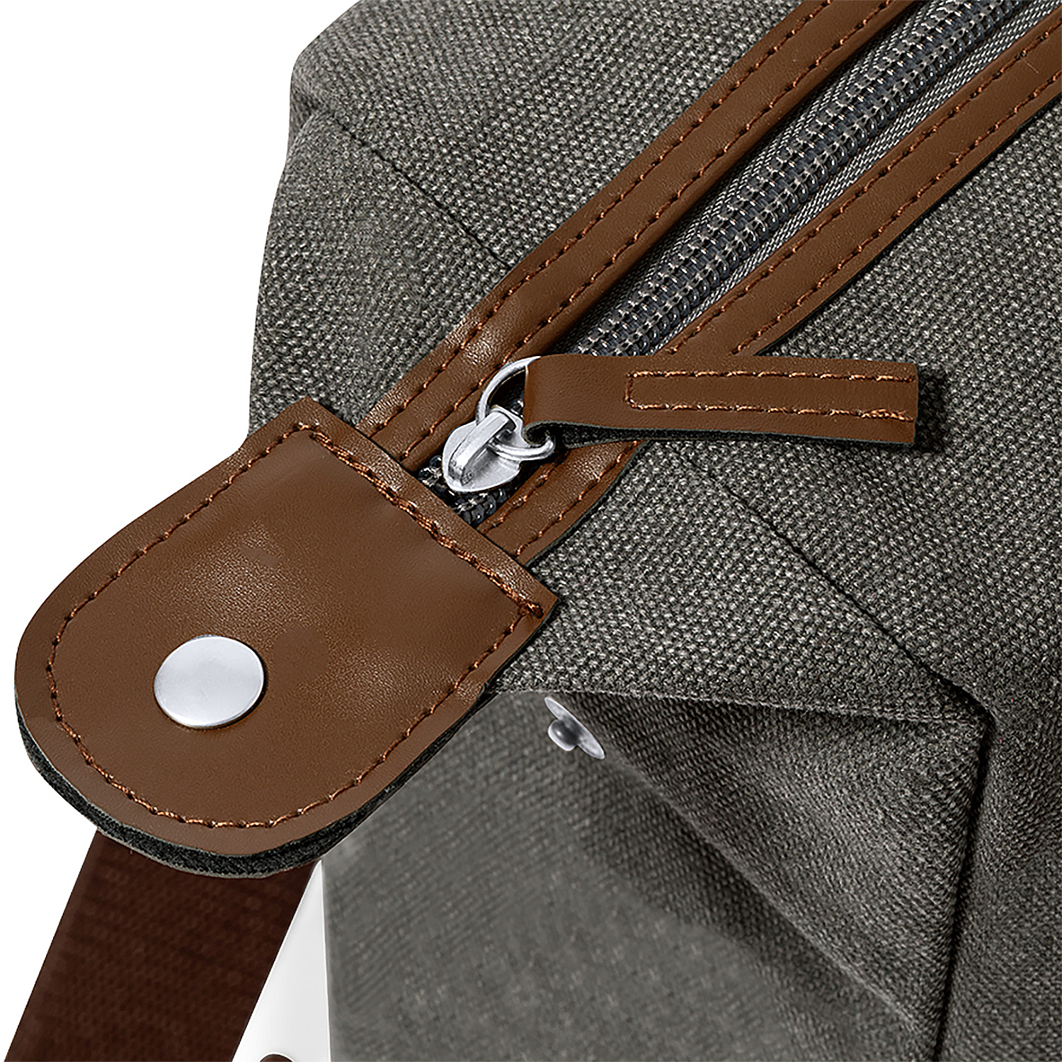 Primo piano di una borsa di tela con tiretto in pelle marrone e cerniera argentata.