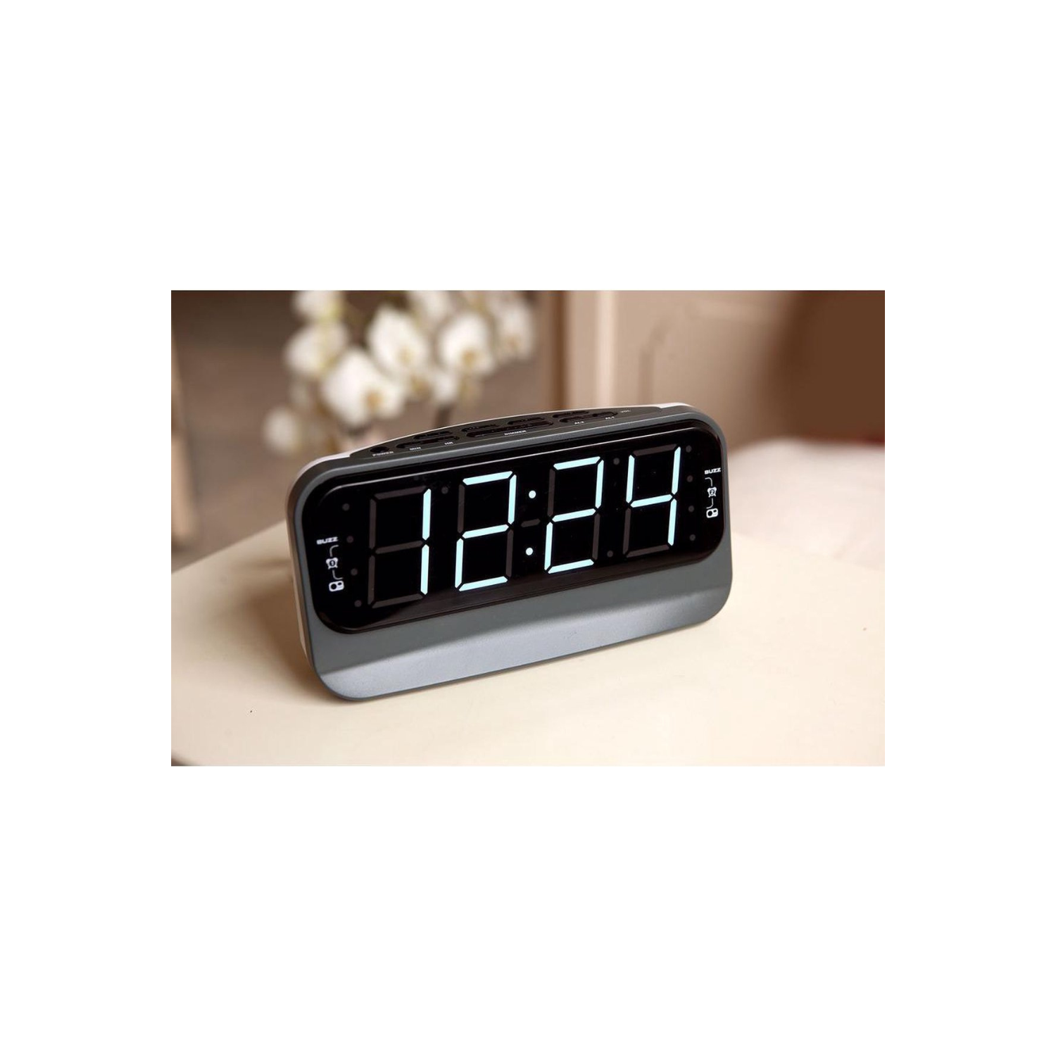 Digital alarm clock displaying 12:24 in large, white LED numbers on a gray body.