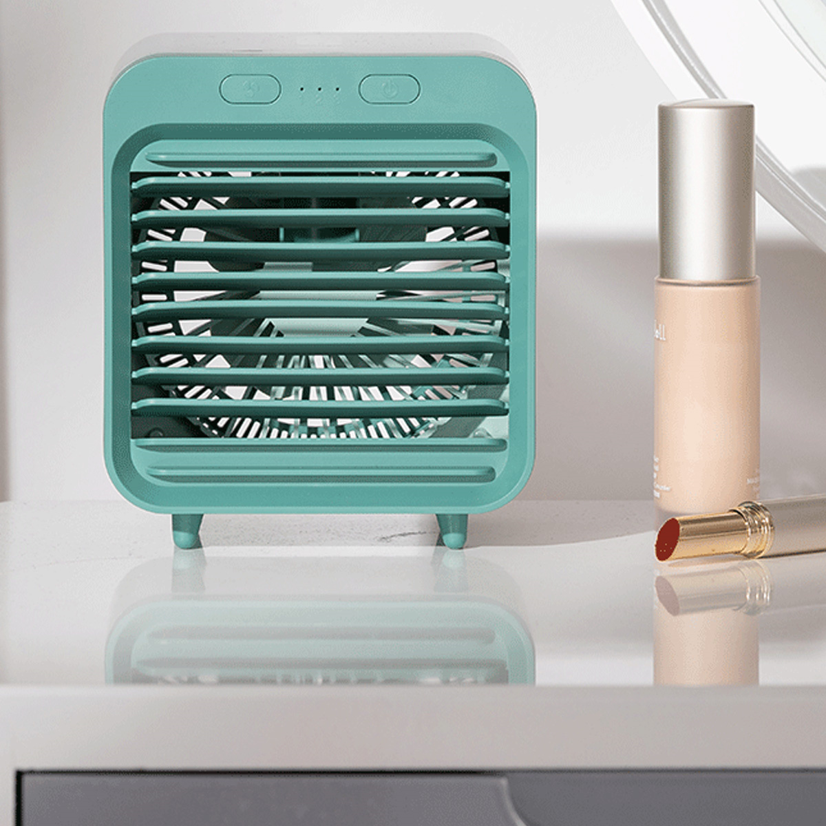 Ein kleiner türkisfarbener Luftkühler mit einem Ventilator, mit einem Lippenstift und einer Foundation-Flasche.