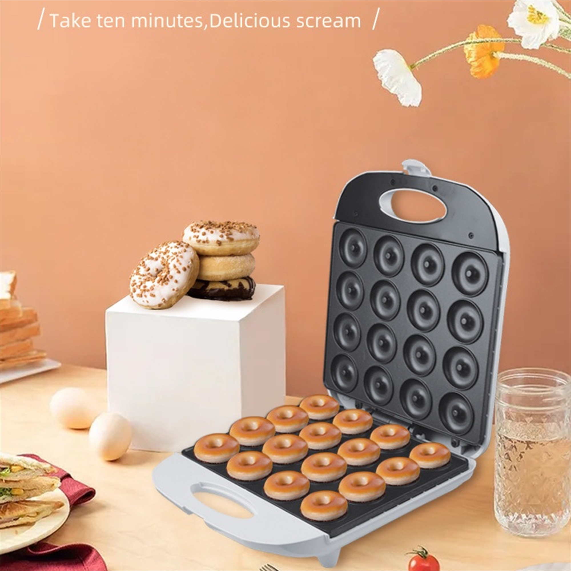Donut-Maker mit gebackenen Donuts, Eiern und einem Glas Wasser. Pfirsichfarbener Hintergrund.
