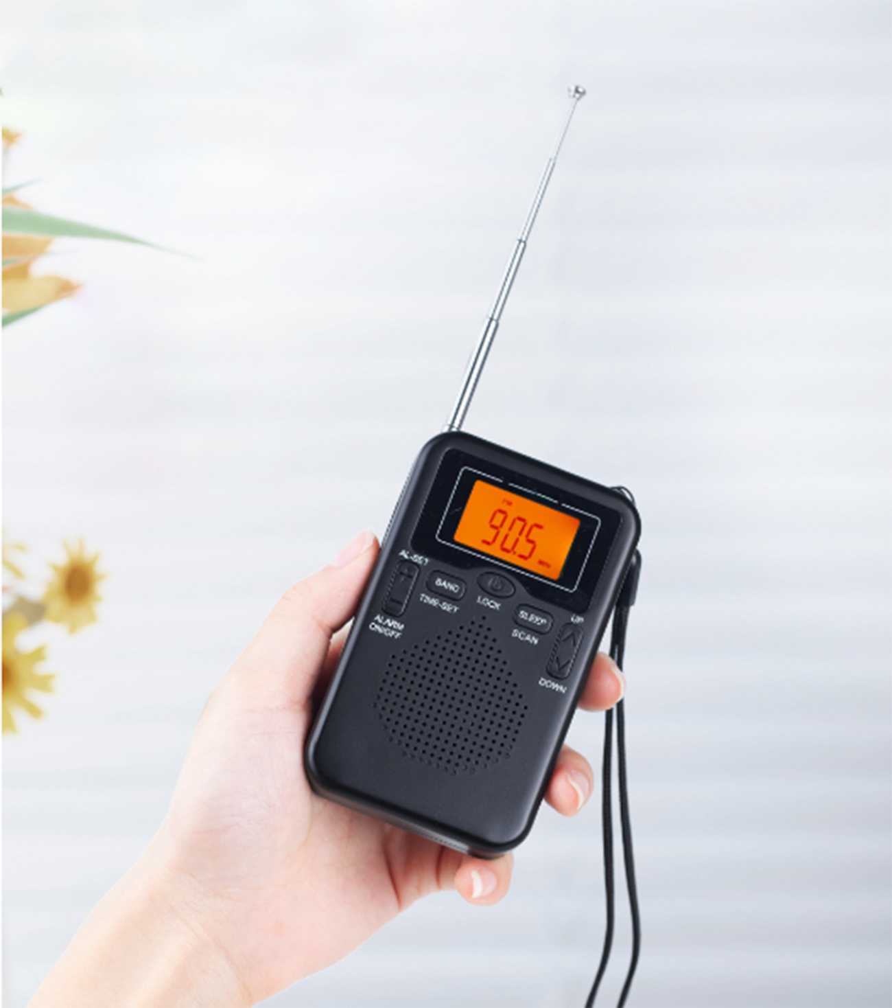 Die Hand einer Person, die ein schwarzes tragbares Radio mit orangefarbener Anzeige hält.