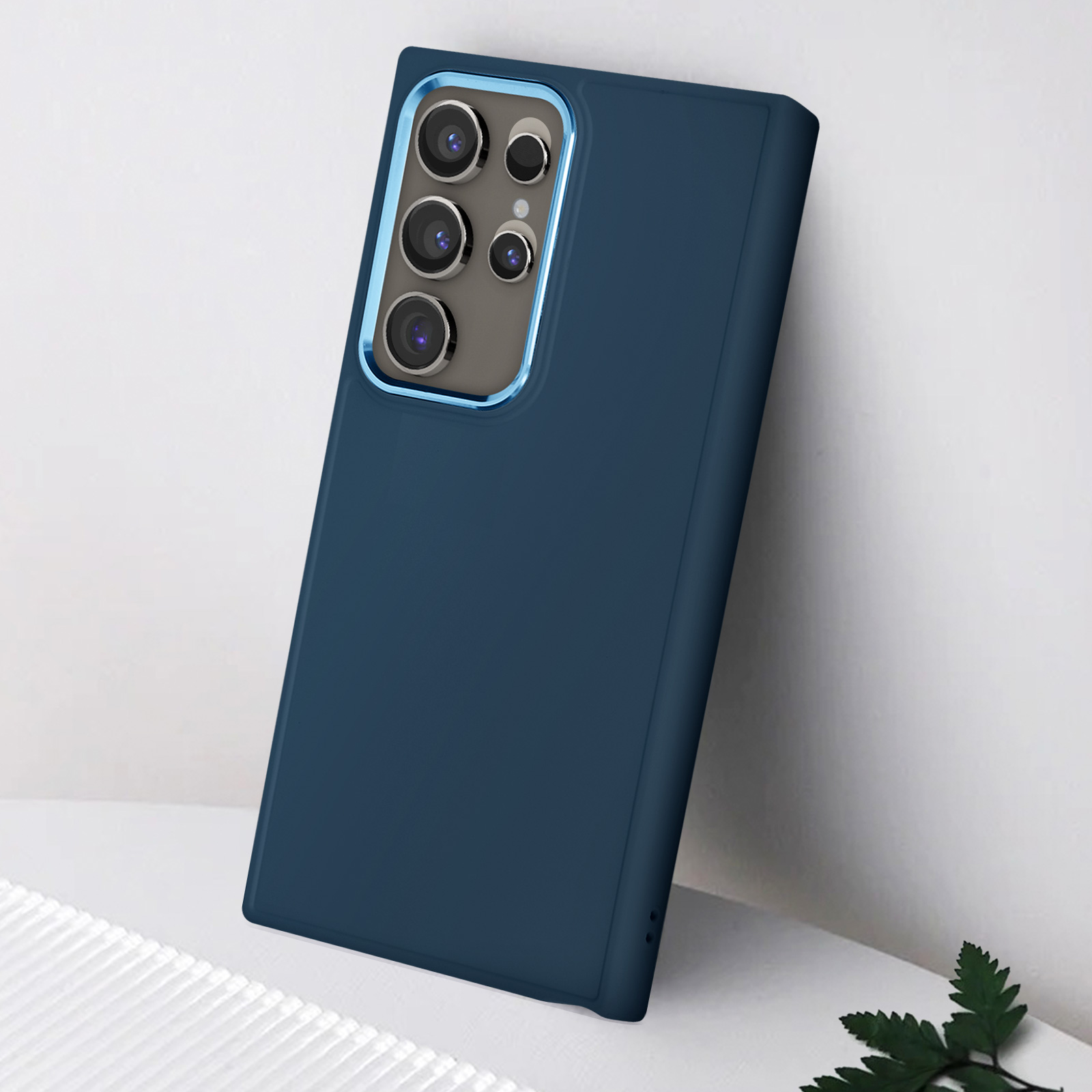 Una custodia blu per telefono con più fotocamere. È su una superficie bianca e vicino a una pianta.