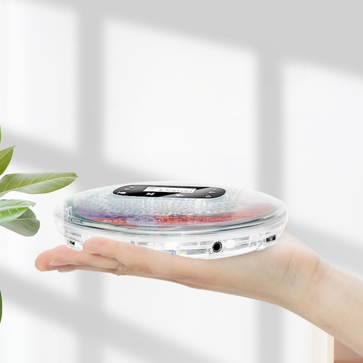 Hand, die einen durchsichtigen tragbaren CD-Player mit einer CD darin hält.