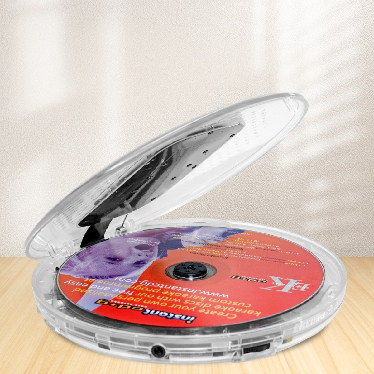 Ein klarer CD-Player mit einer Disc. Das Gehäuse ist geöffnet und liegt auf einer Holzoberfläche.
