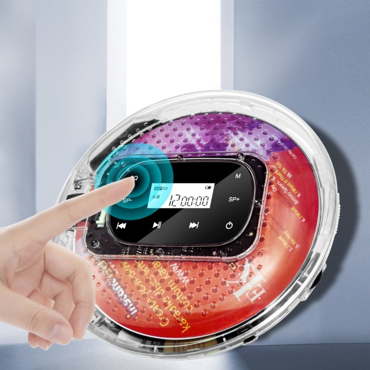 Eine Hand berührt einen tragbaren CD-Player. Display zeigt 12:00:00. Die Disc ist sichtbar.