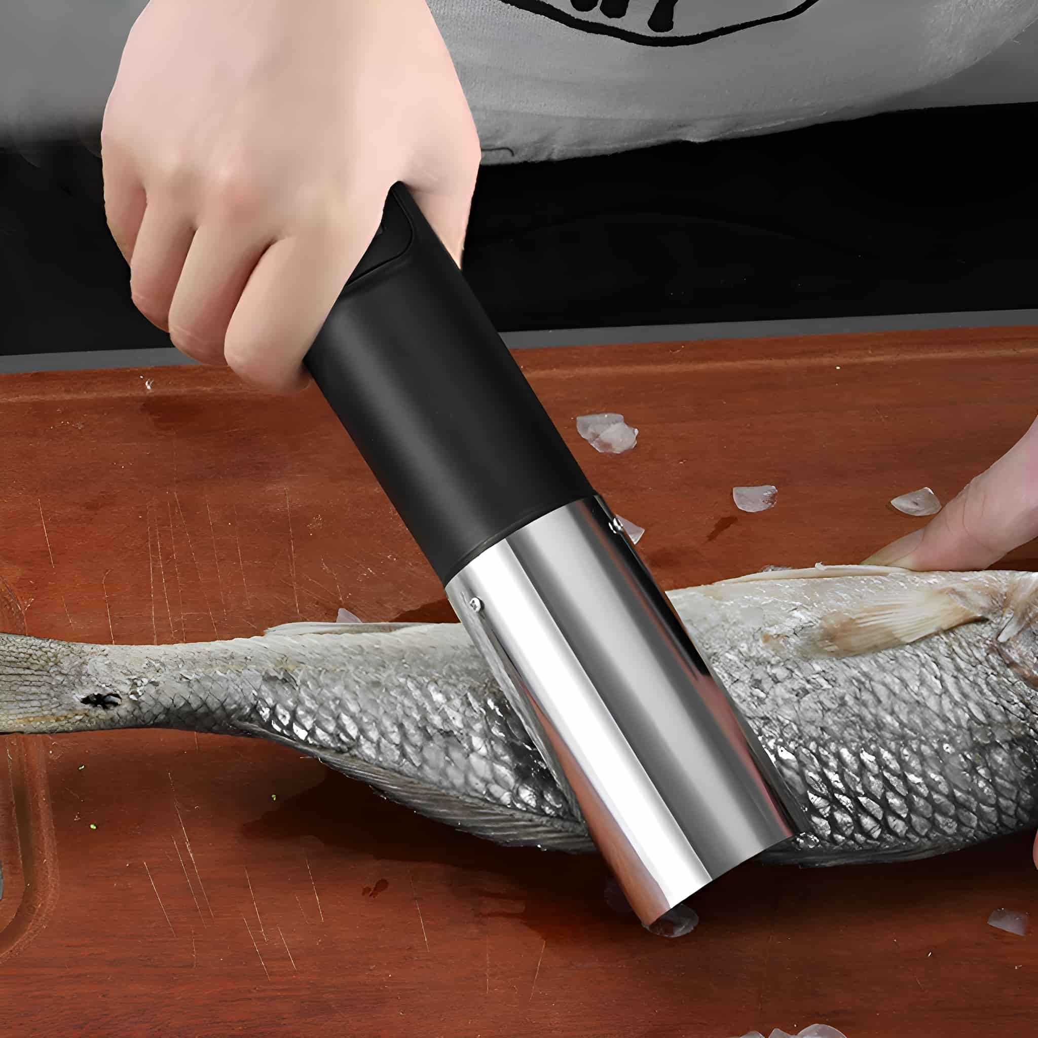 Eine Hand benutzt einen schwarz-silbernen Fischschupper auf einem Fisch auf einem Holzbrett.