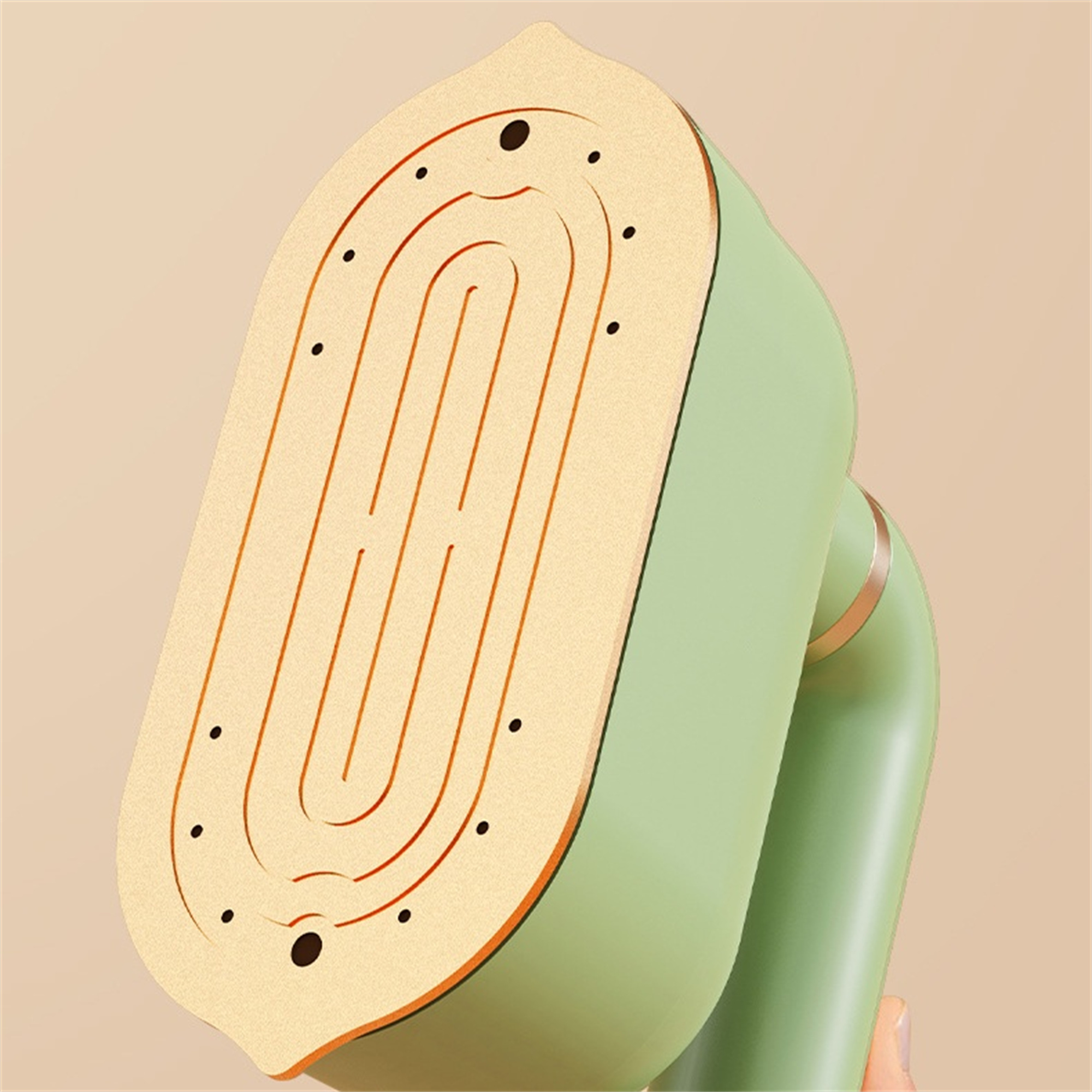 Grüner und beigefarbener Handdampfer, ovale Form mit Löchern, auf neutralem Hintergrund.