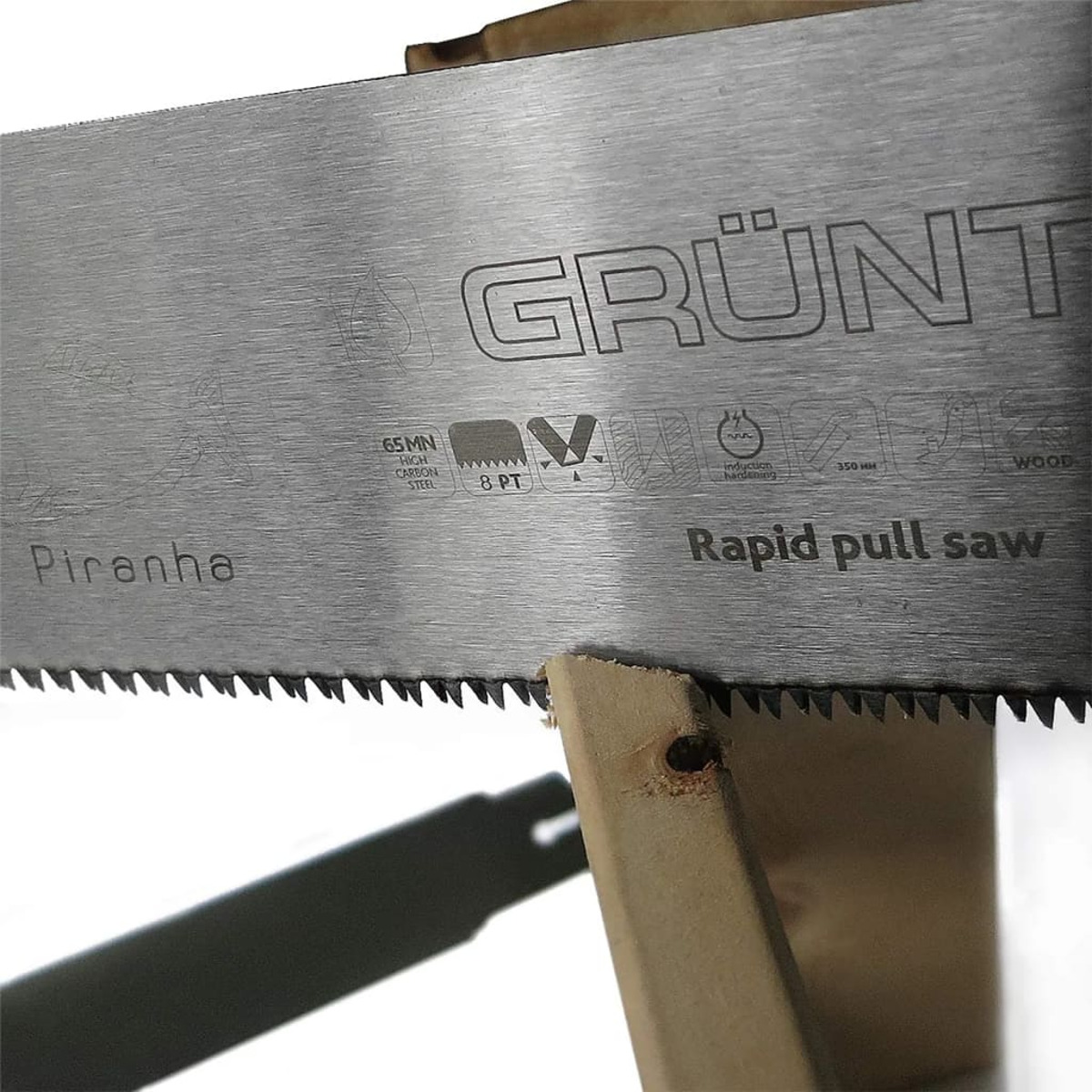 Ein Sägeblatt mit den Aufschriften "GRUNT" und "Piranha" auf einer Holzunterstützung.