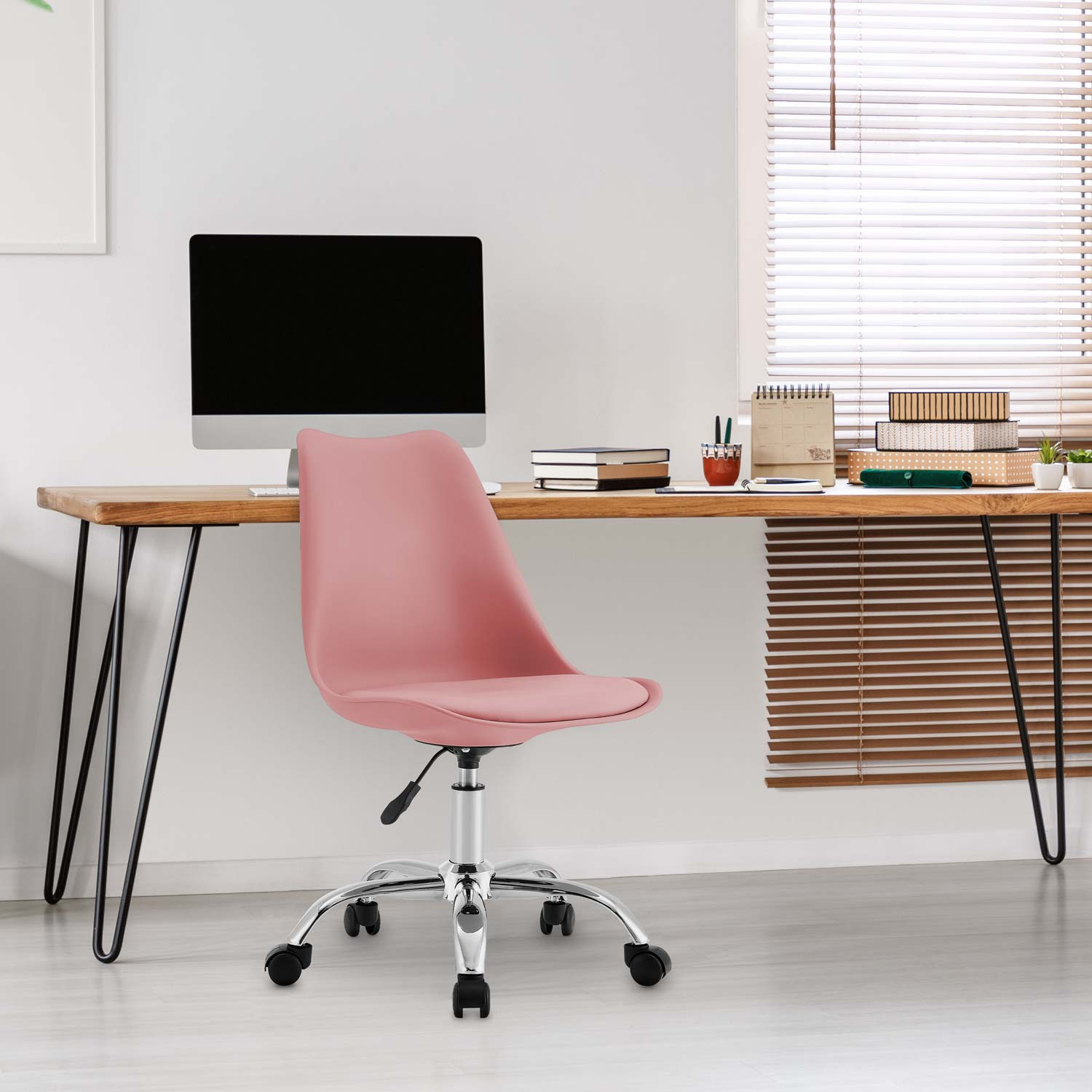 Silla de oficina rosa frente a escritorio de madera con computadora, libros y persianas.