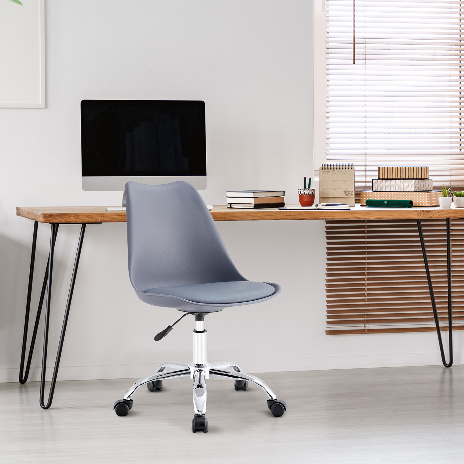 Interior de oficina con silla gris, escritorio de madera, computadora y persianas. Paredes blancas.