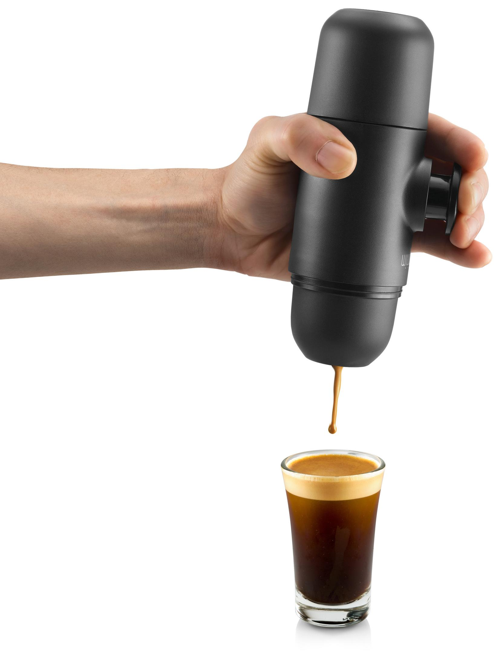 Hand hält einen schwarzen Espressomaschine, Kaffee in ein Glas gießen.