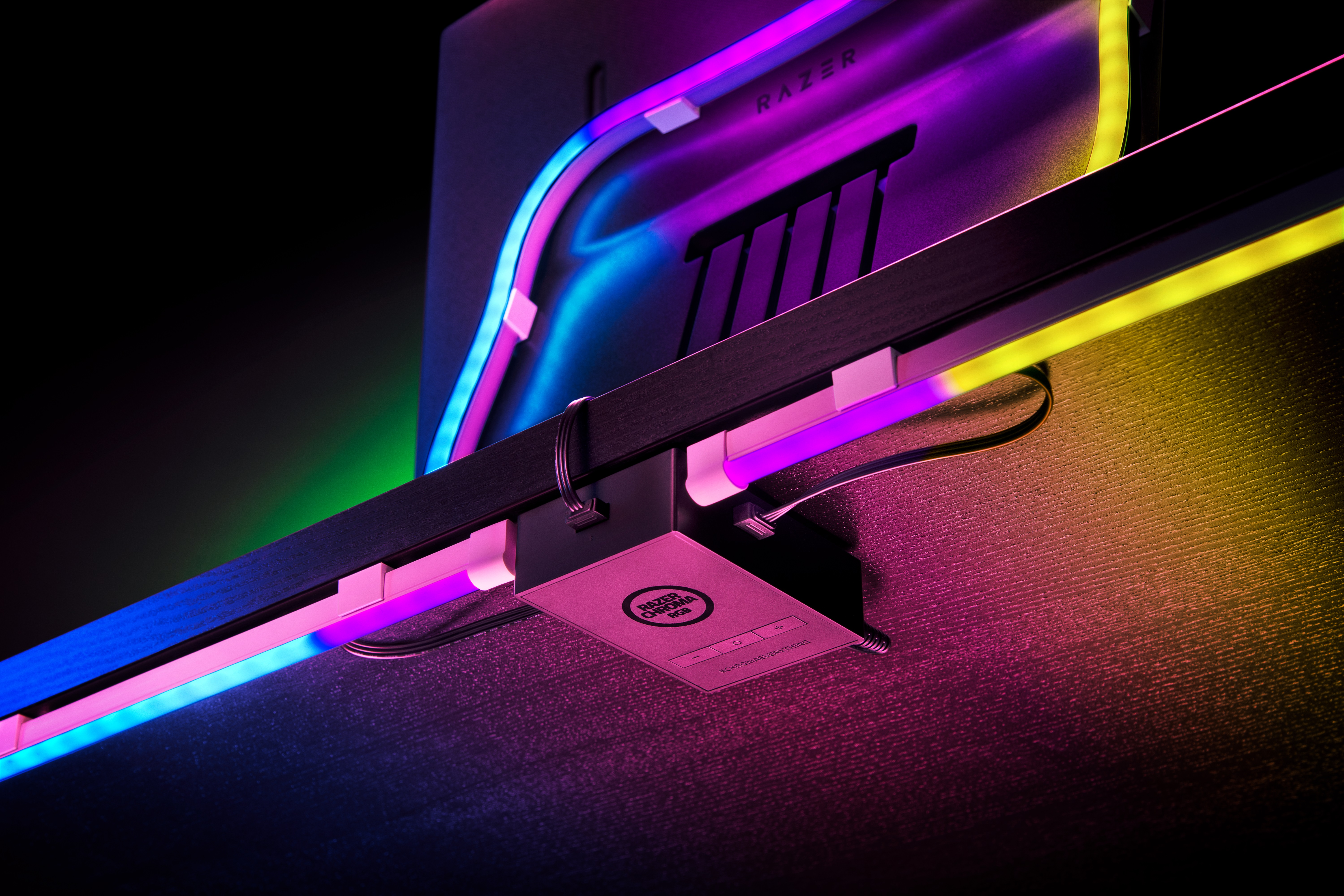 Schreibtisch-Setup mit RGB-Beleuchtung, einem Razer-Monitor und einem Schreibtisch-Organizer. Die Szene ist dunkel mit leuchtenden Neonfarben.