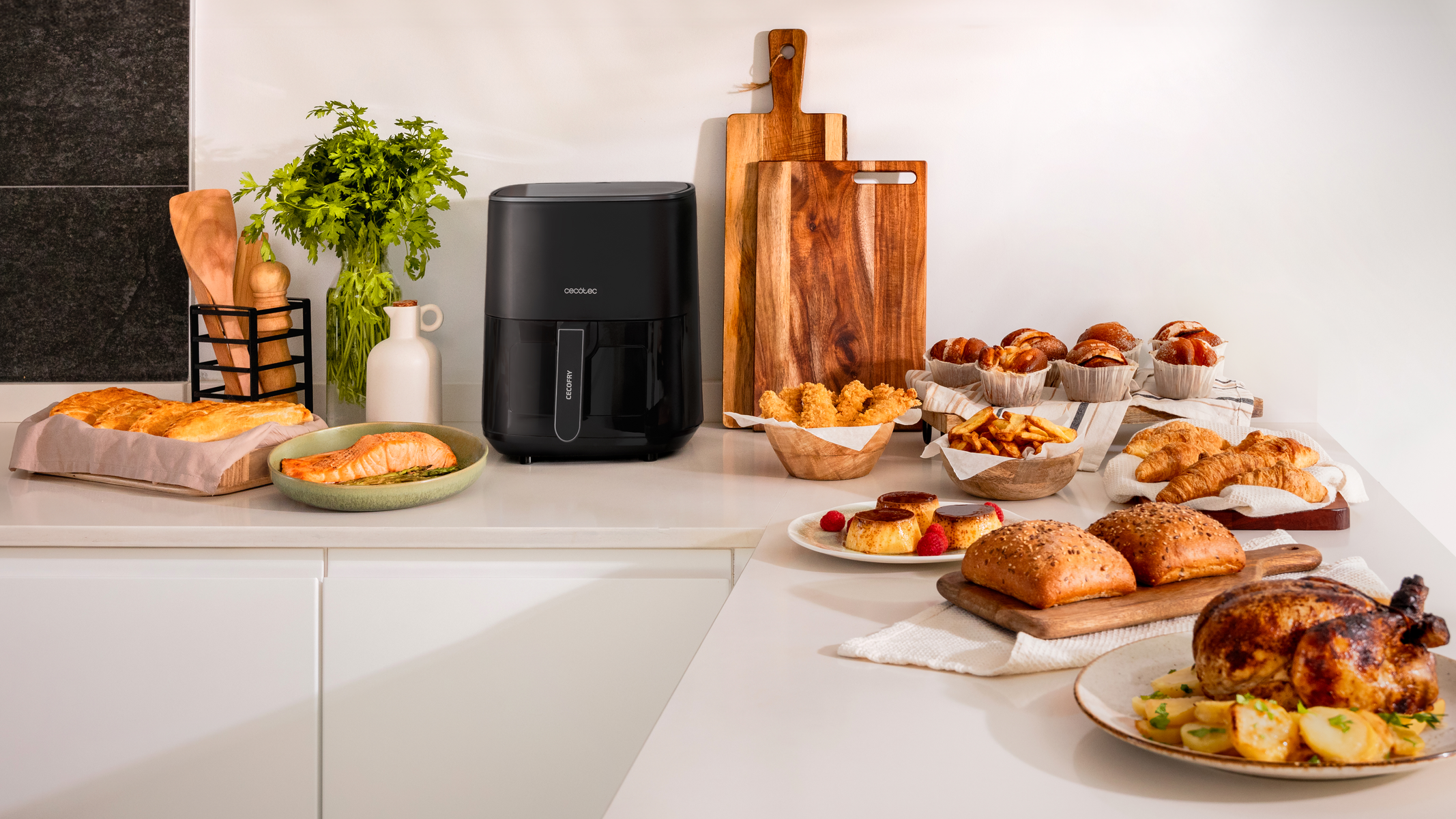 Una encimera de cocina muestra una freidora de aire, alimentos y algunos utensilios de cocina.