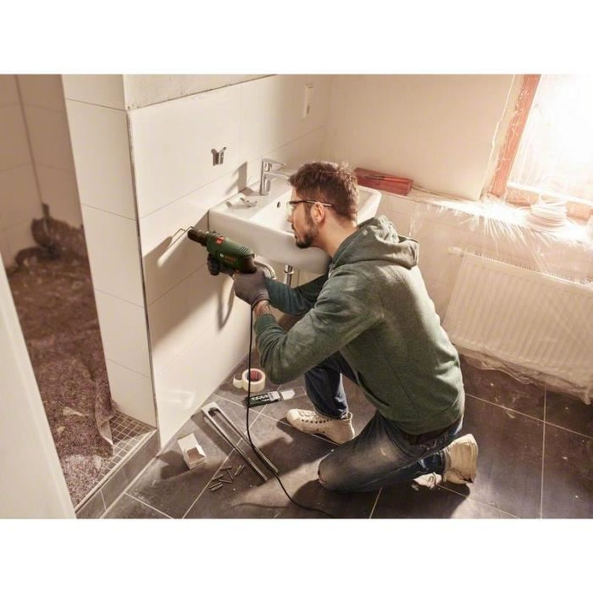 Un hombre trabajando en una pared en un baño.
