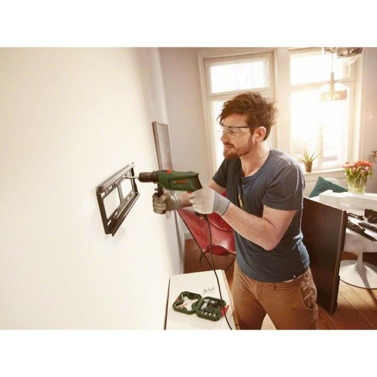 Un hombre perforando una pared para instalar un soporte.