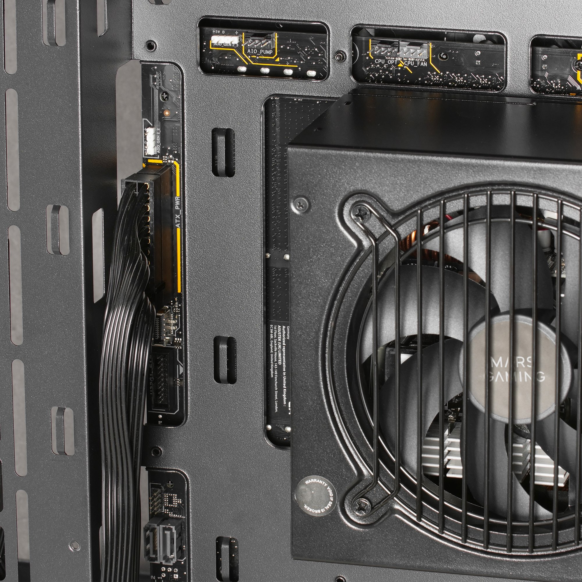 Wnętrze obudowy komputera, pokazujące zasilacz, wentylator i kable.