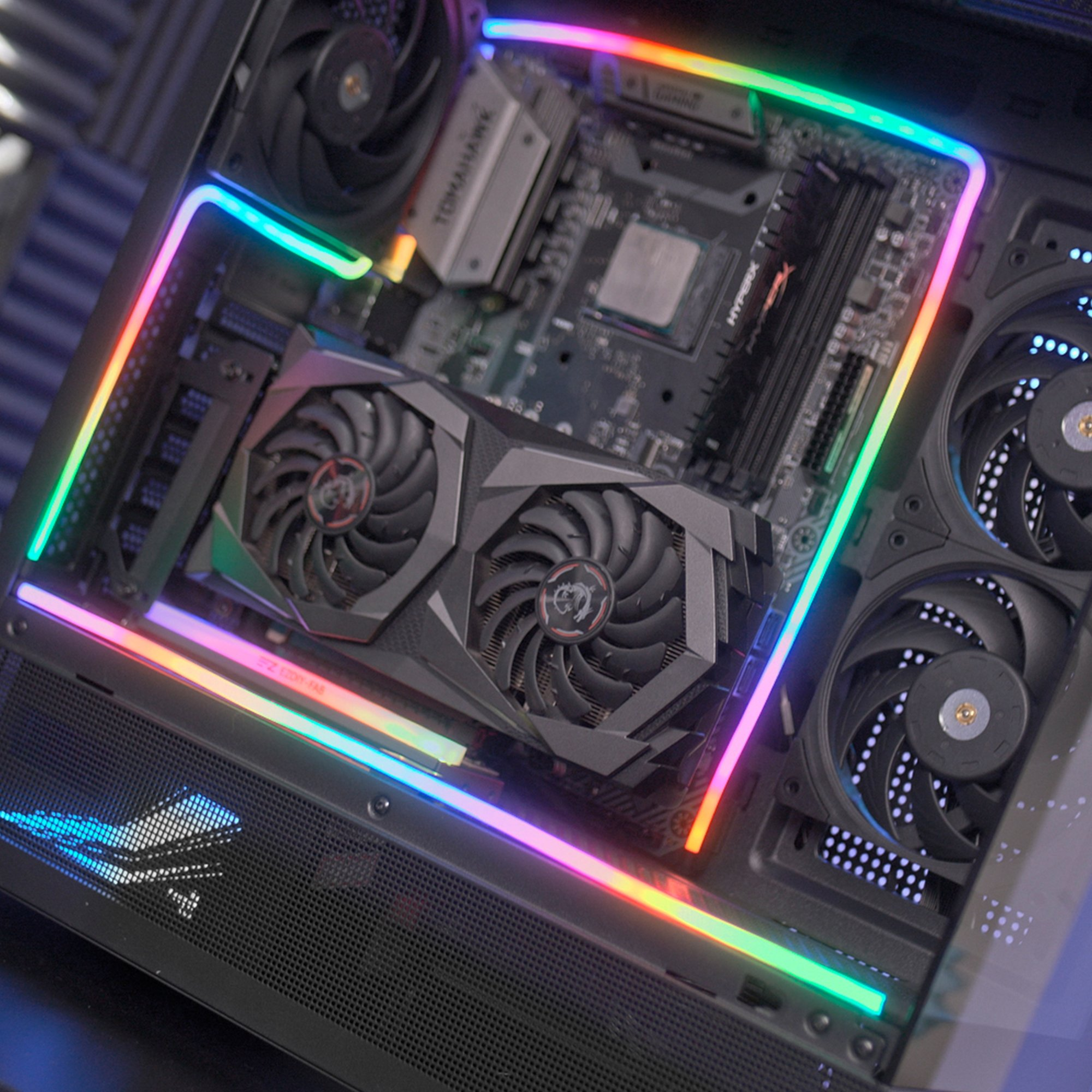 Dentro de una caja de computadora, se ven una tarjeta gráfica, ventiladores y una placa base con iluminación RGB.