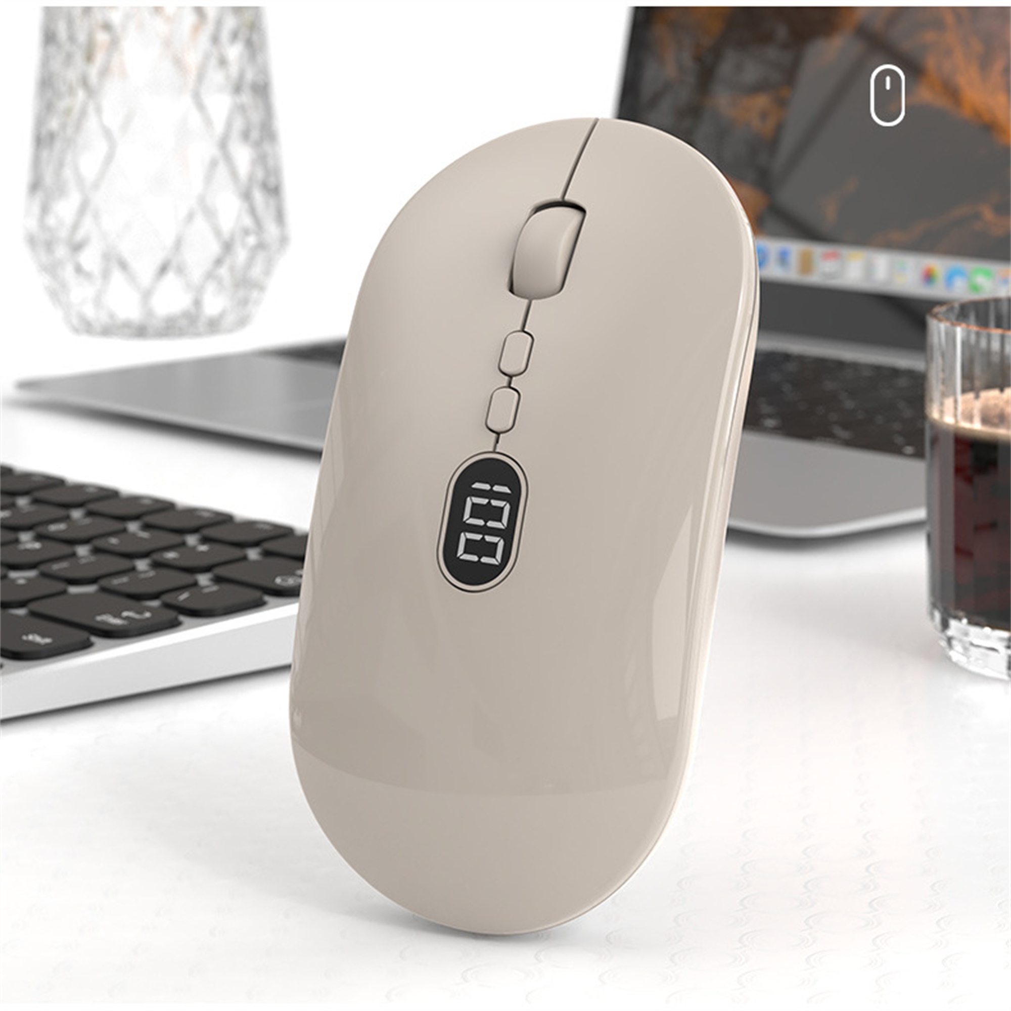 Beige kabellose Maus mit Display, auf einem Schreibtisch mit Tastatur, Glas und Kaffee.