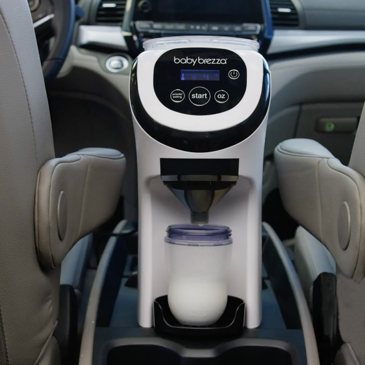Weiß-schwarzer Baby-Formelzubereiter in der Konsole eines Autos. Eine Flasche füllt sich.