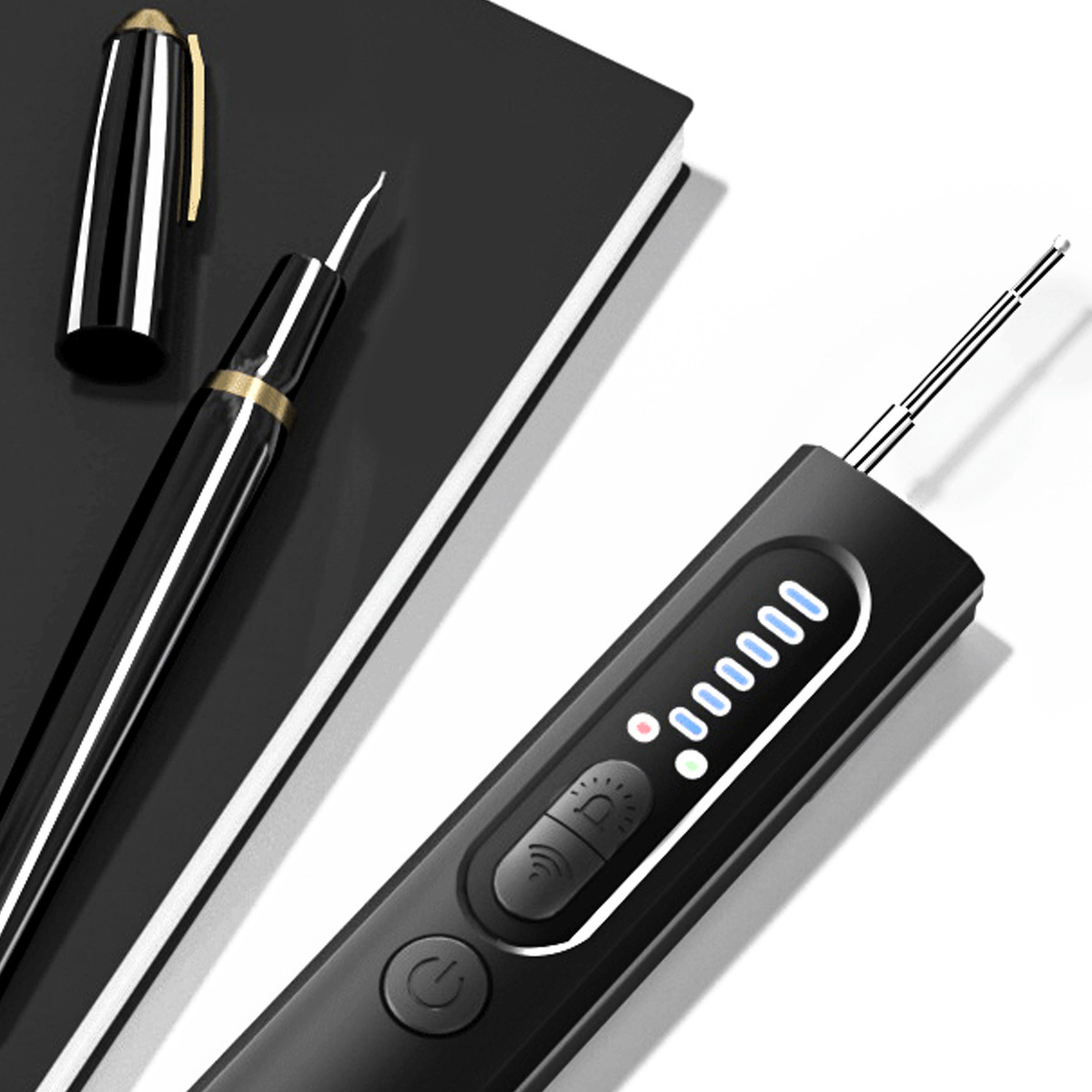 Ein Stift und ein schwarzes Gerät mit Lichtern und einem Knopf. Ein Notizbuch im Hintergrund.