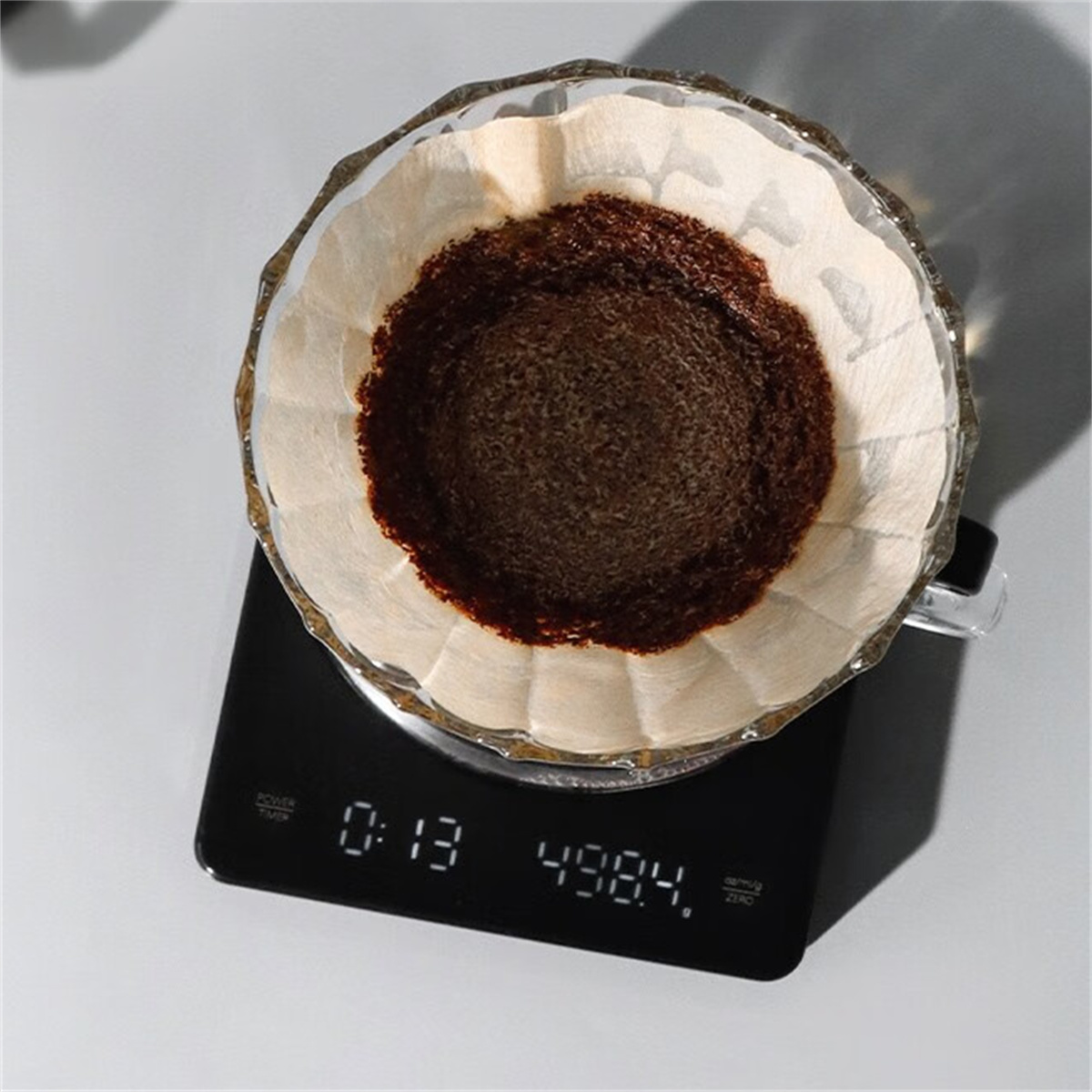 Kaffeezubereitung. Glasfilter mit Kaffeesatz auf einer schwarzen Waage.