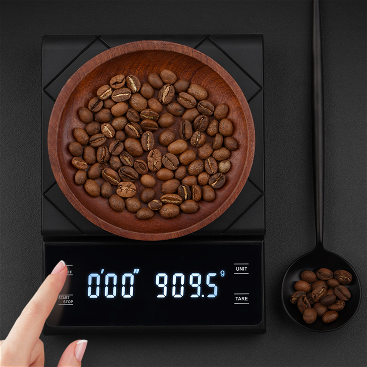 Digitale Küchenwaage mit Kaffeebohnen auf einem Holzbrett. Eine Hand berührt das Display.
