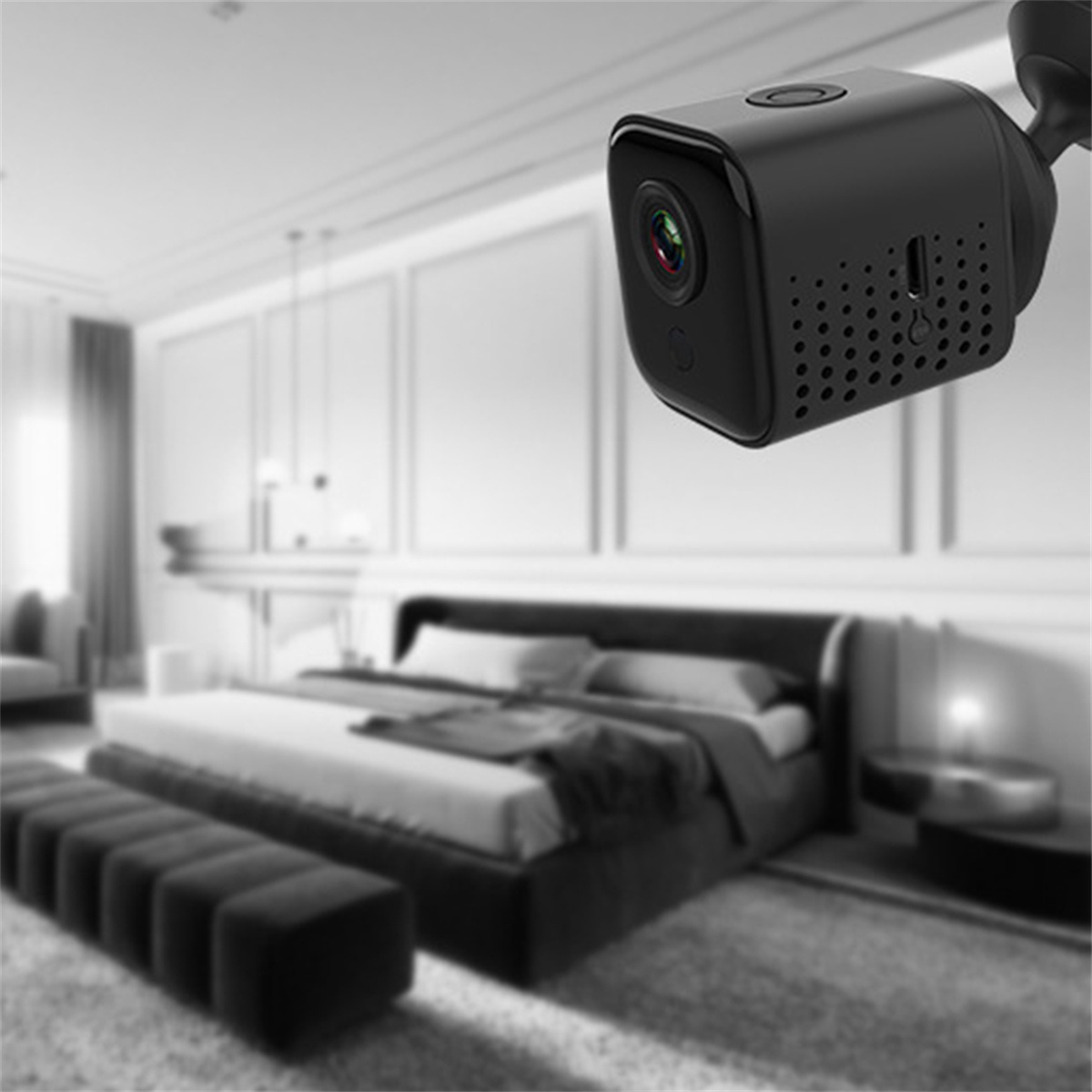 Eine kleine schwarze Überwachungskamera hängt in einem Raum. Der Raum ist verschwommen mit einem Bett und einer Couch im Hintergrund.