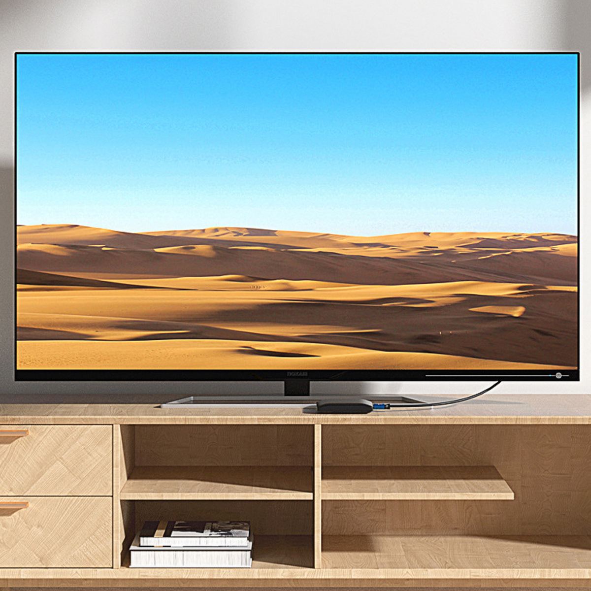 Fernseher mit Wüstenlandschaft auf Holzschrank. Blauer Himmel im Hintergrund.
