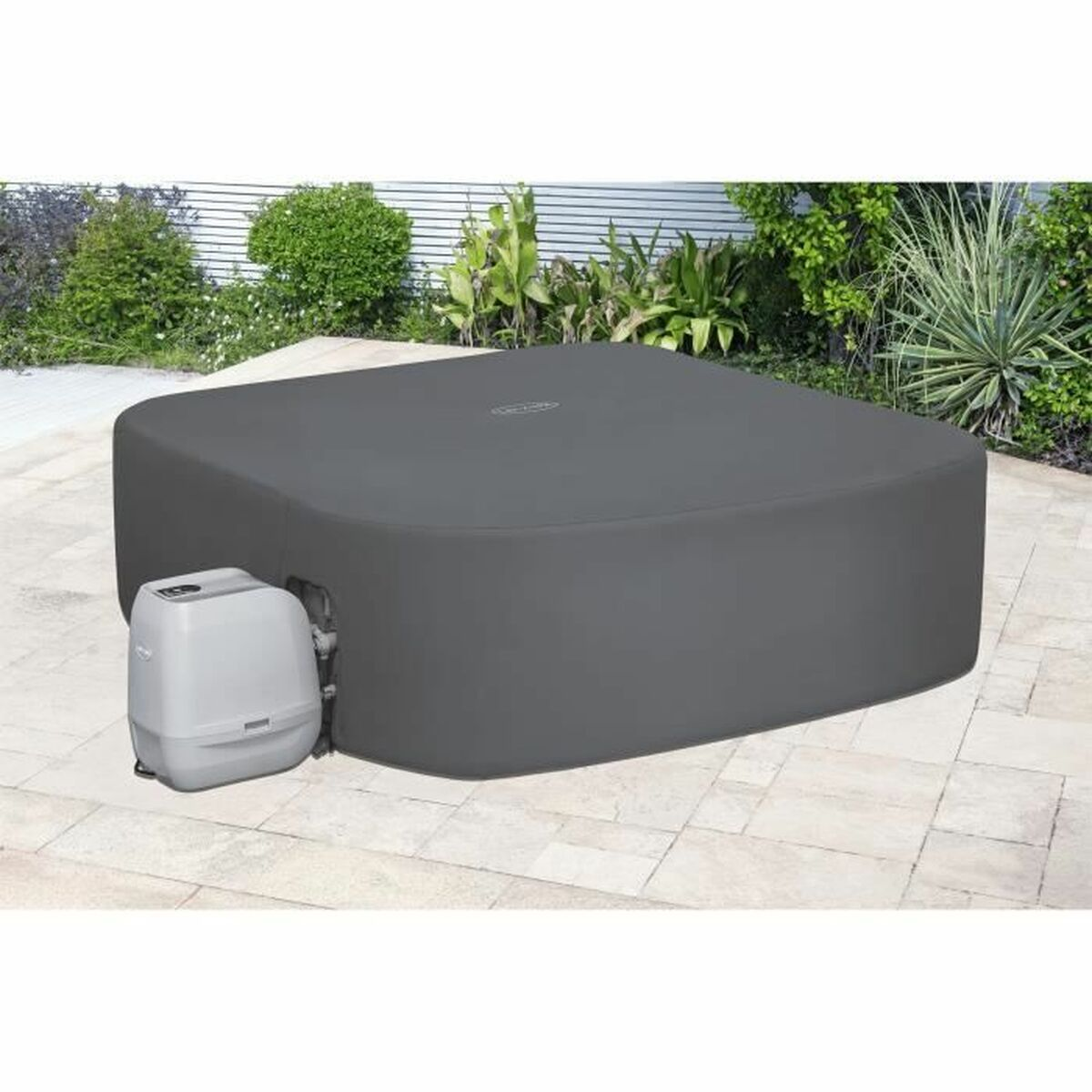 Ein quadratischer Whirlpool mit dunkelgrauer Abdeckung auf einer Terrasse. Links eine Pumpe.