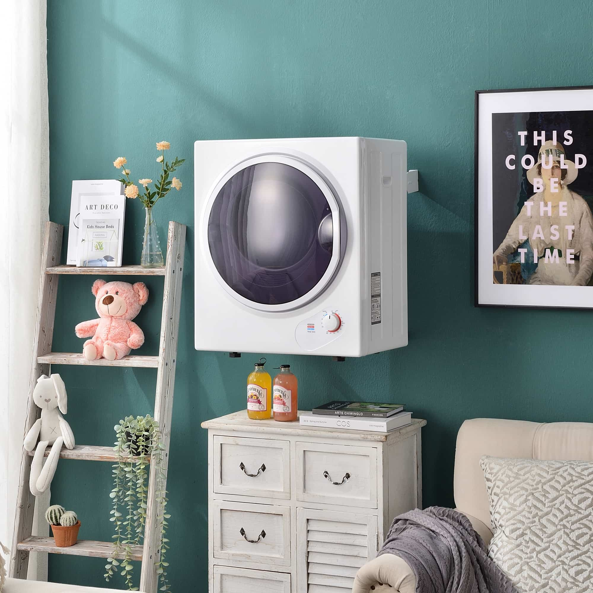 Ein weißer, an der Wand befestigter Trockner mit kleiner Leiter, Blumen, Teddybär und Bild.