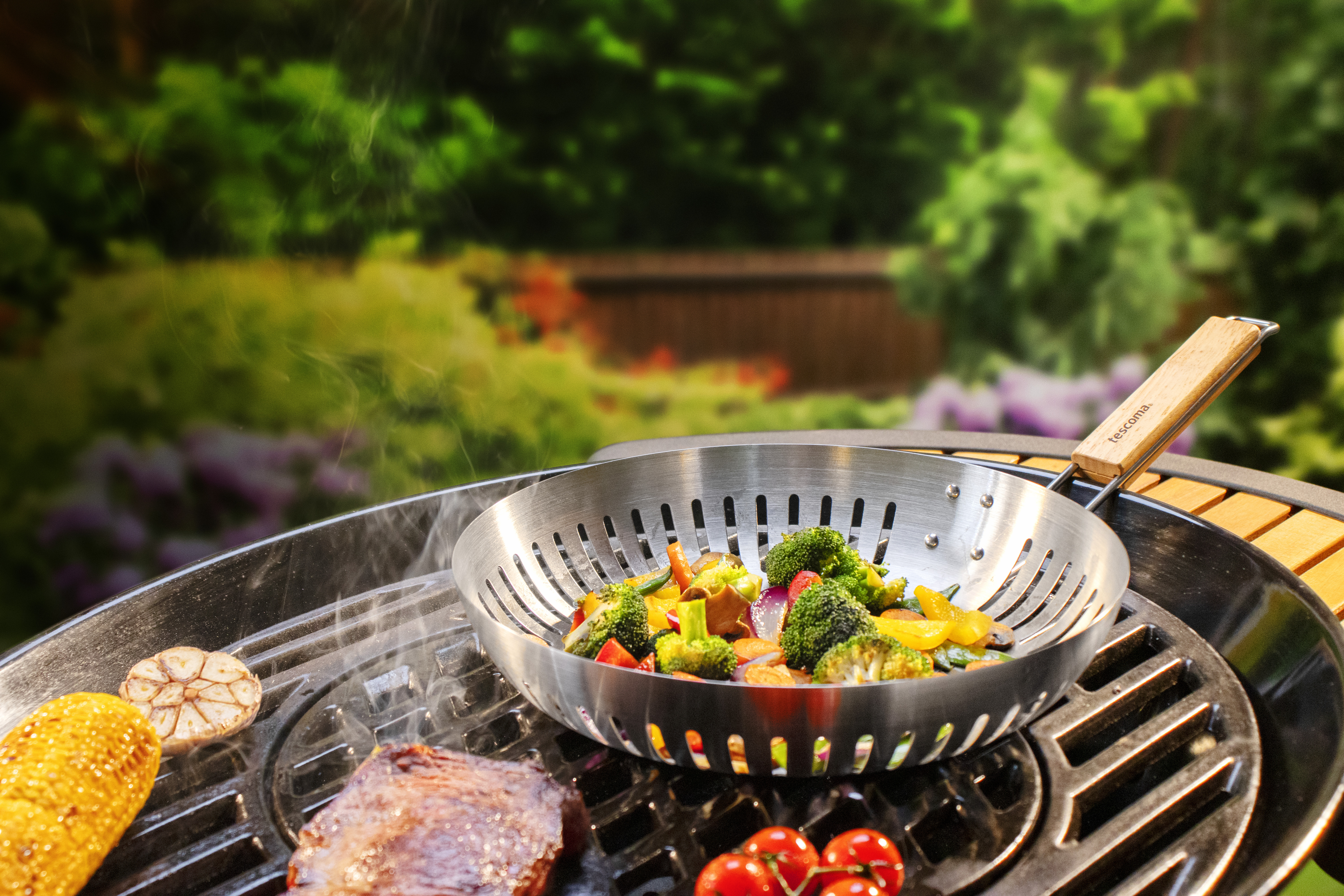 Ein Grill mit Gemüse und einem Steak in einem Wok, mit verschwommenem grünen Hintergrund.