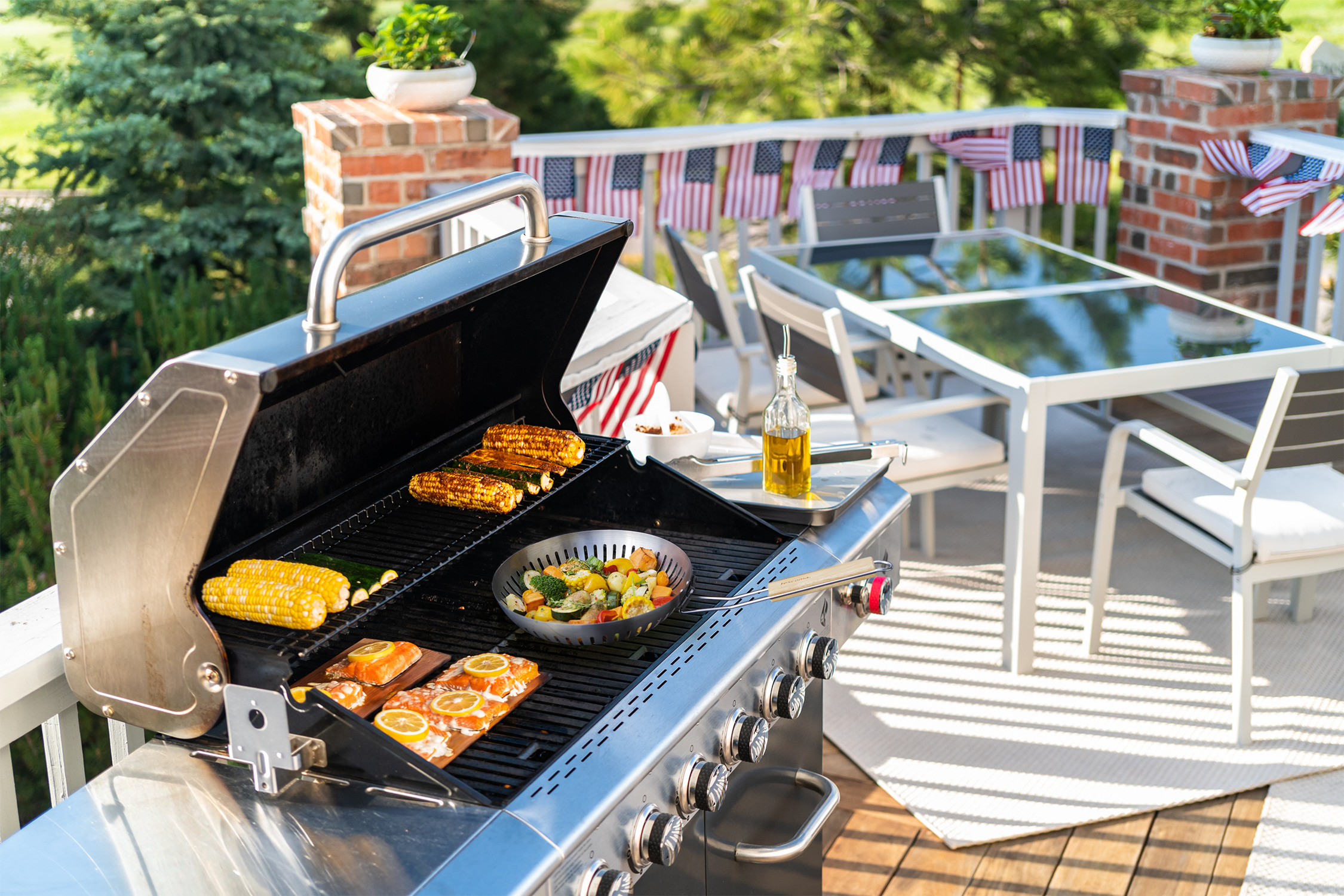 Außengrill mit Essen. Mais, Gemüse und Fisch. Tisch mit Flaggen.