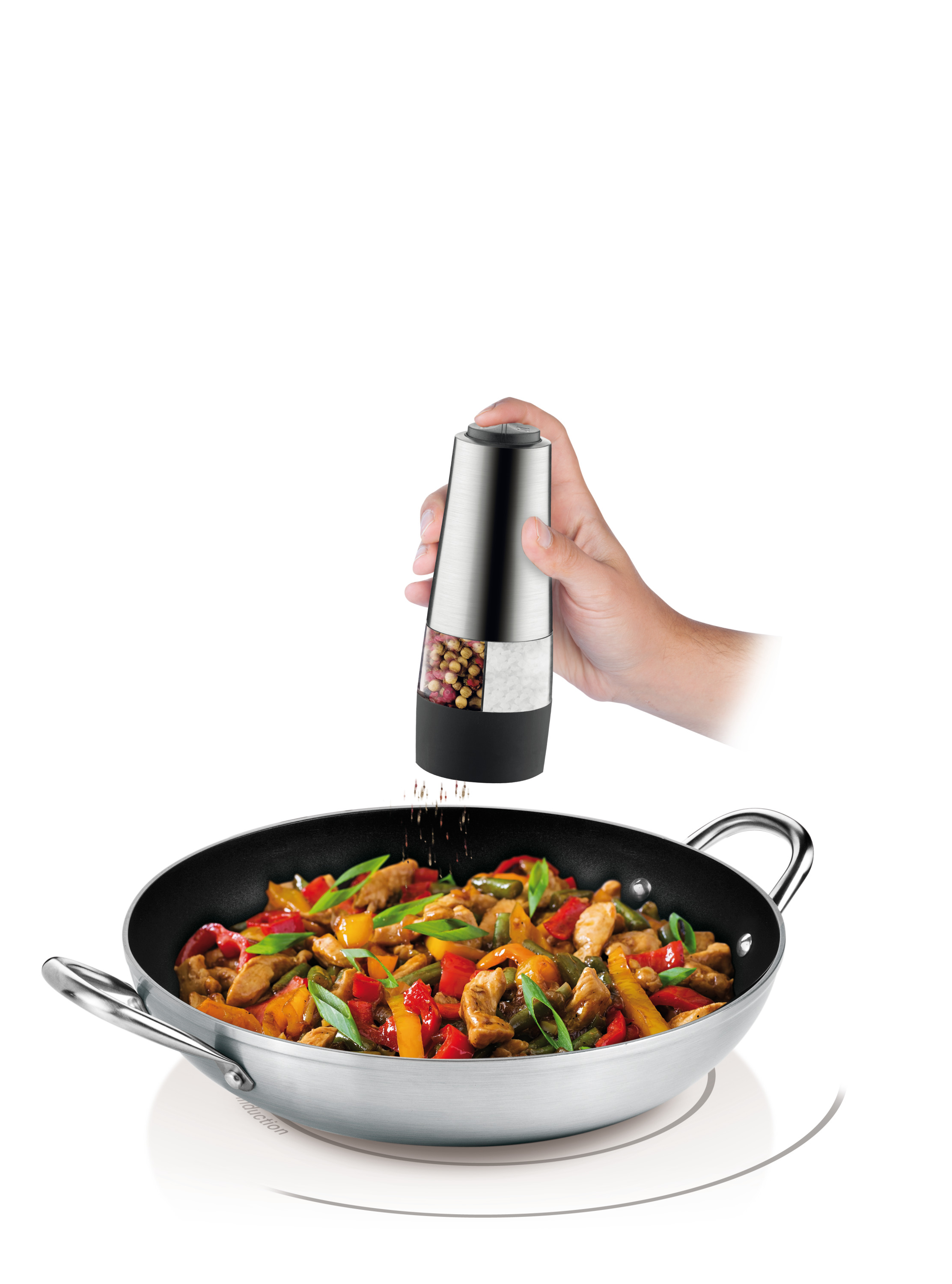 Hand gibt Pfeffer aus einem Edelstahl-Grinder auf ein Pfannengericht. Weißer Hintergrund.